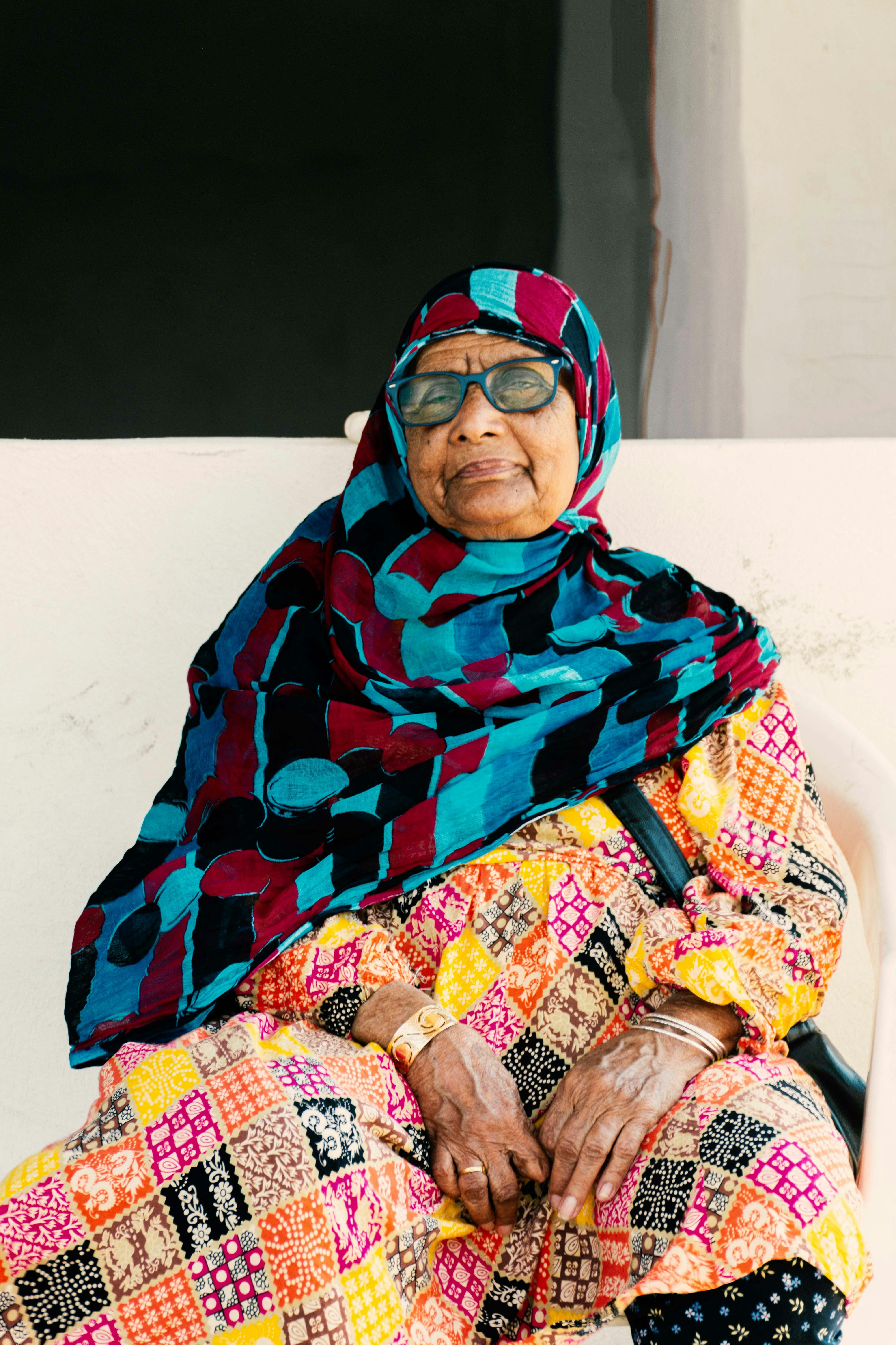 Wanita tua dengan pakaian tradisional dan jilbab berwarna-warni.