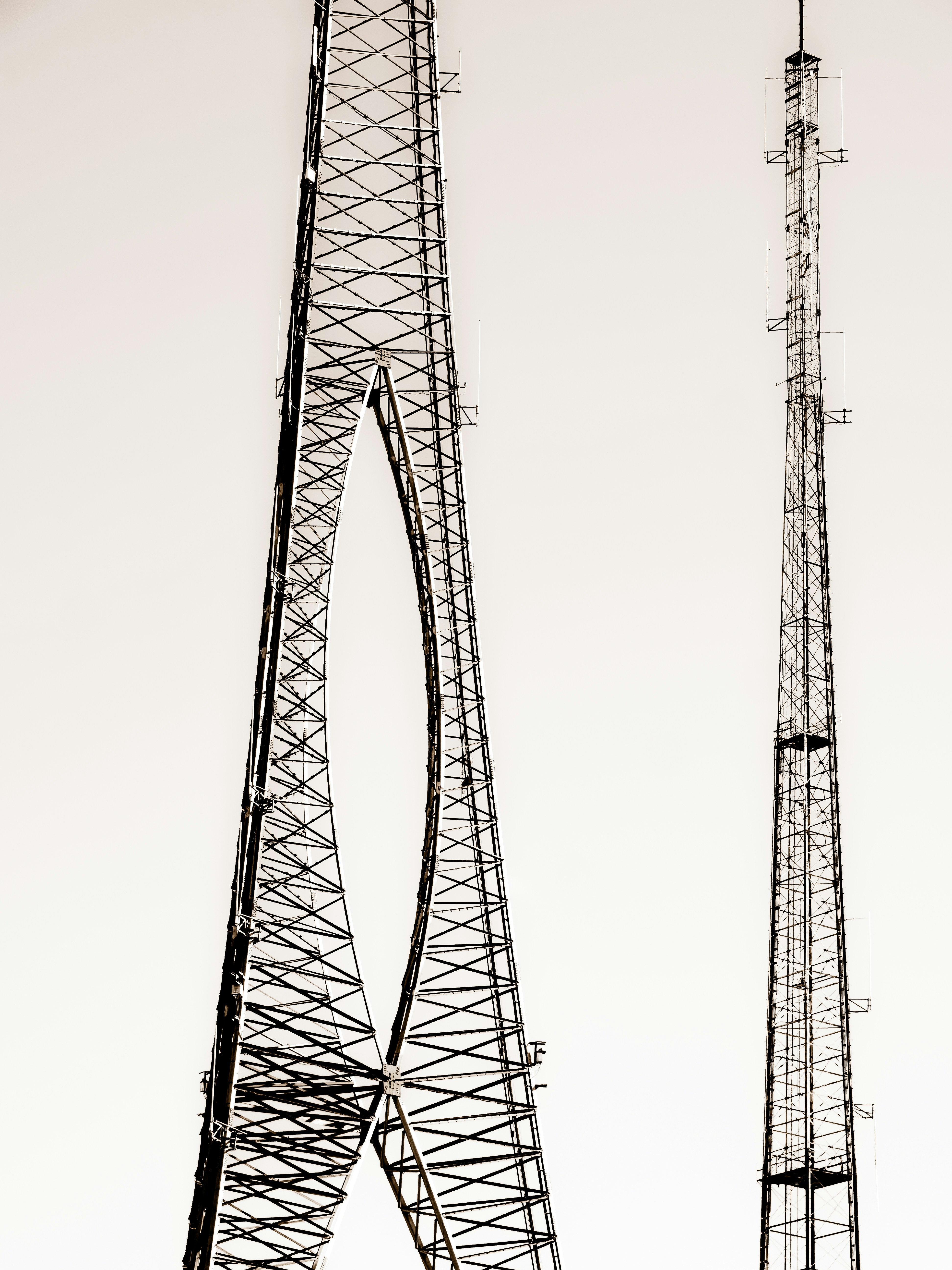 Two tall radio towers against a bright sky