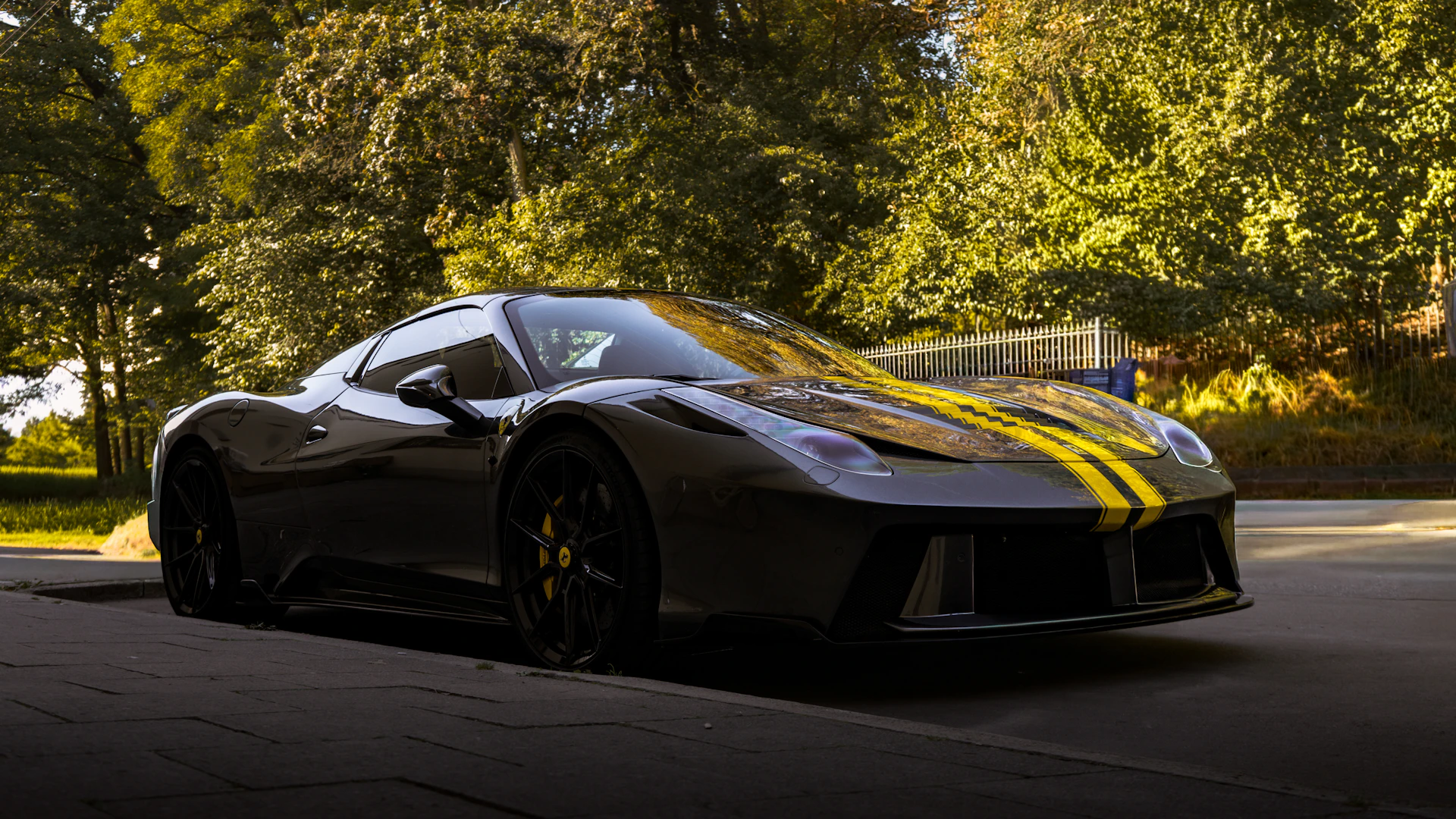 A sleek, dark sports car with yellow racing stripes.