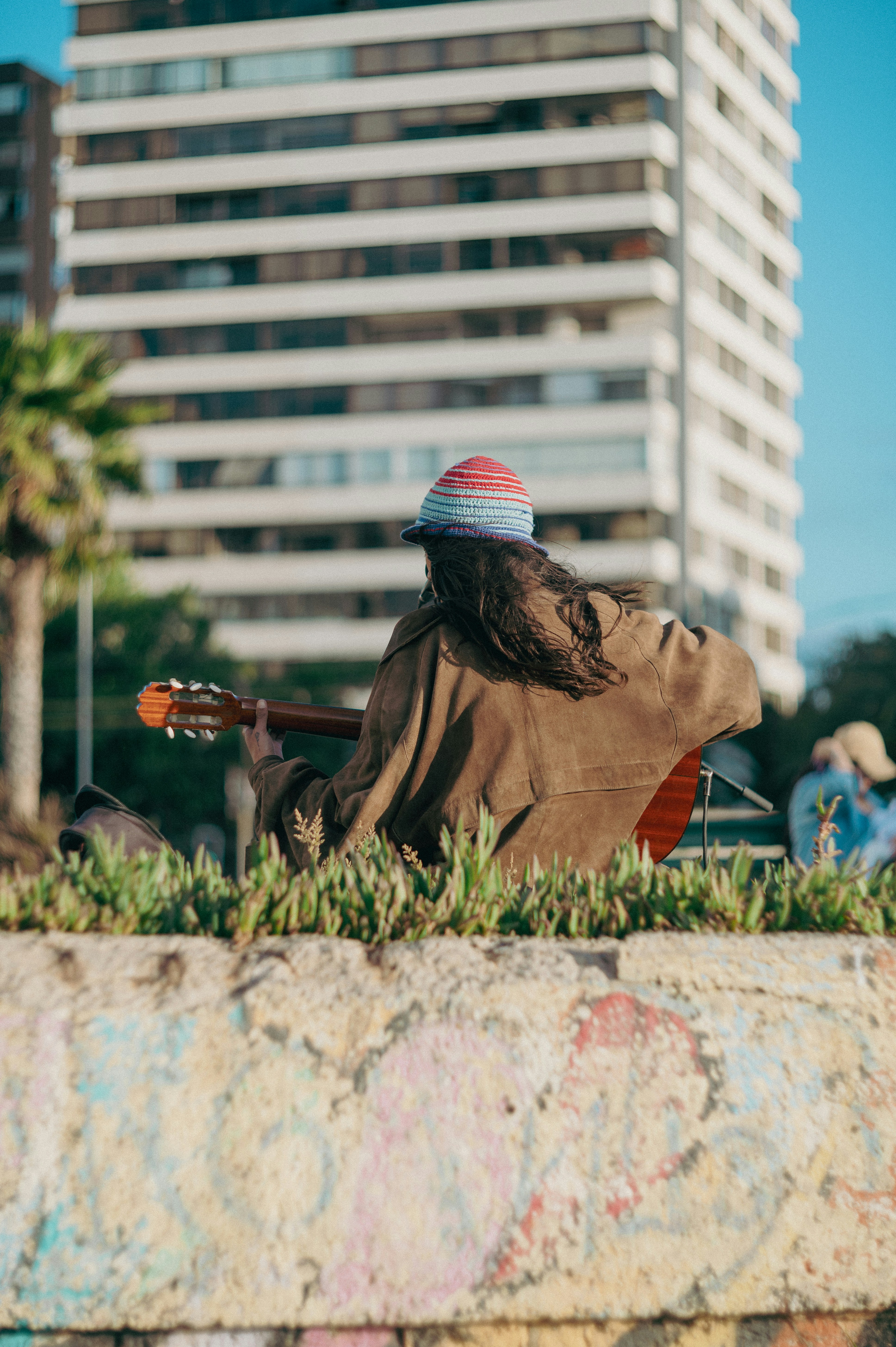 Person playing guitar with building in background