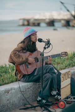 Woman playing guitar and singing by the sea