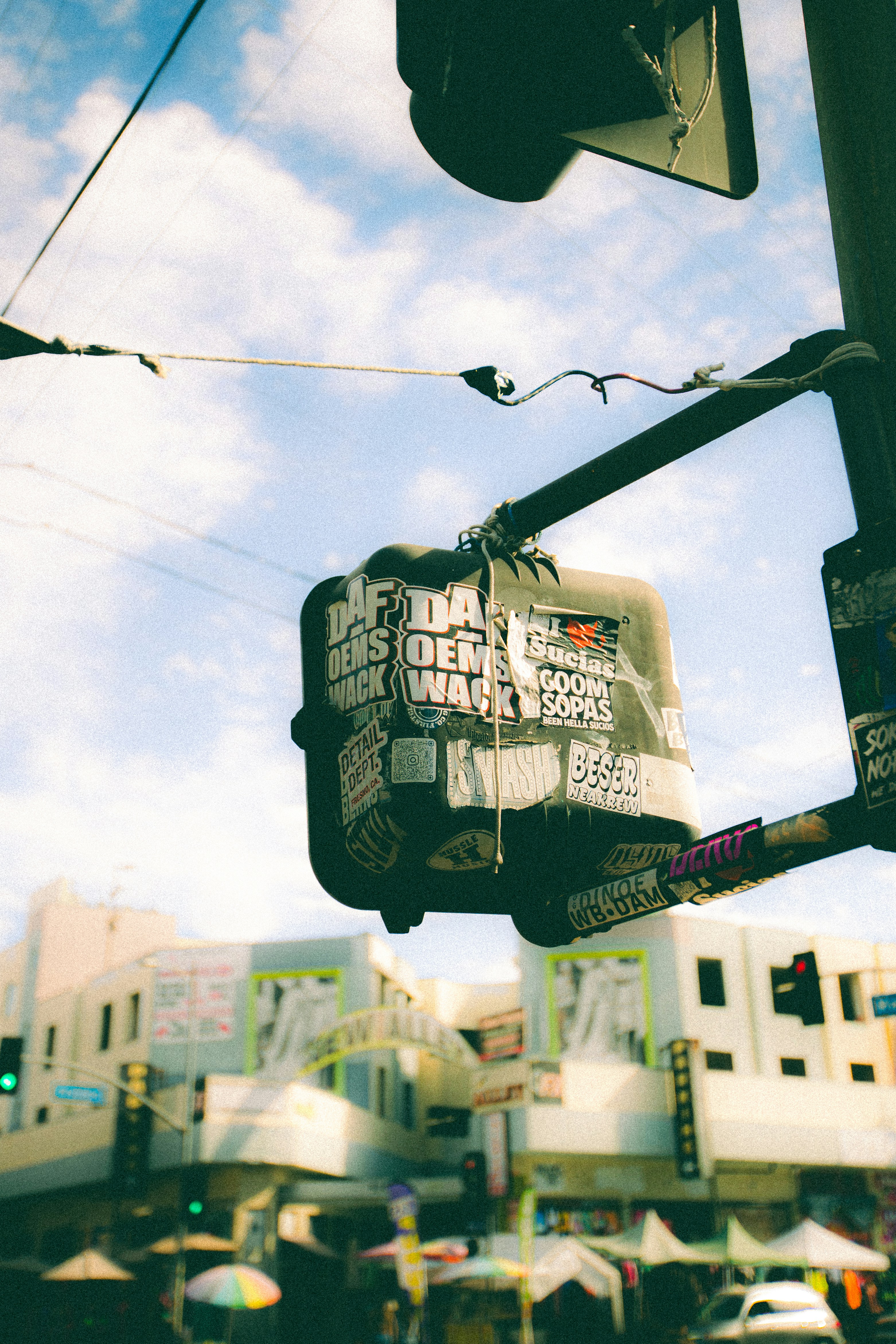 Traffic light covered in stickers with city buildings behind