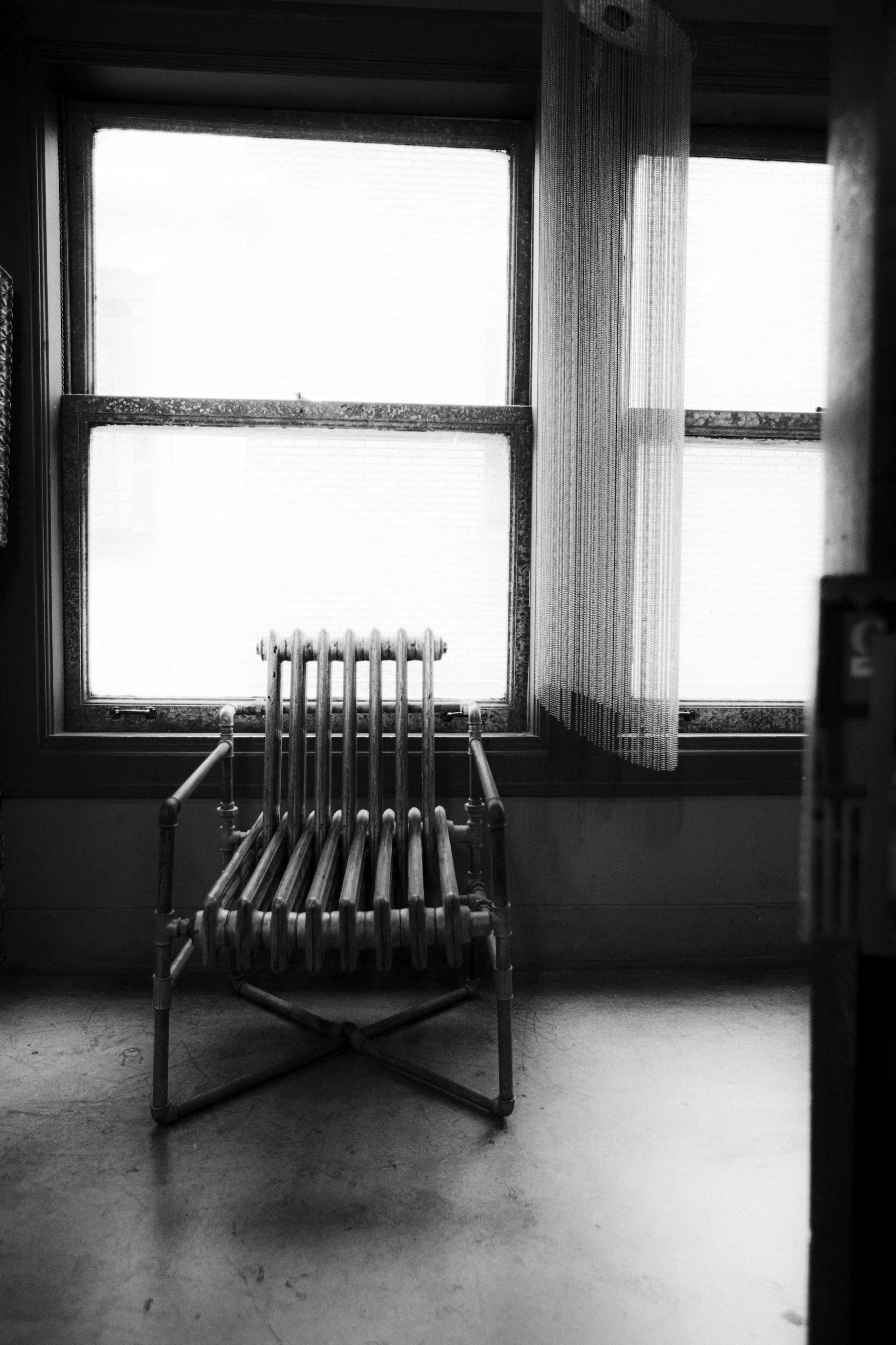 A single unoccupied chair in front of a window, in soft, quiet light.