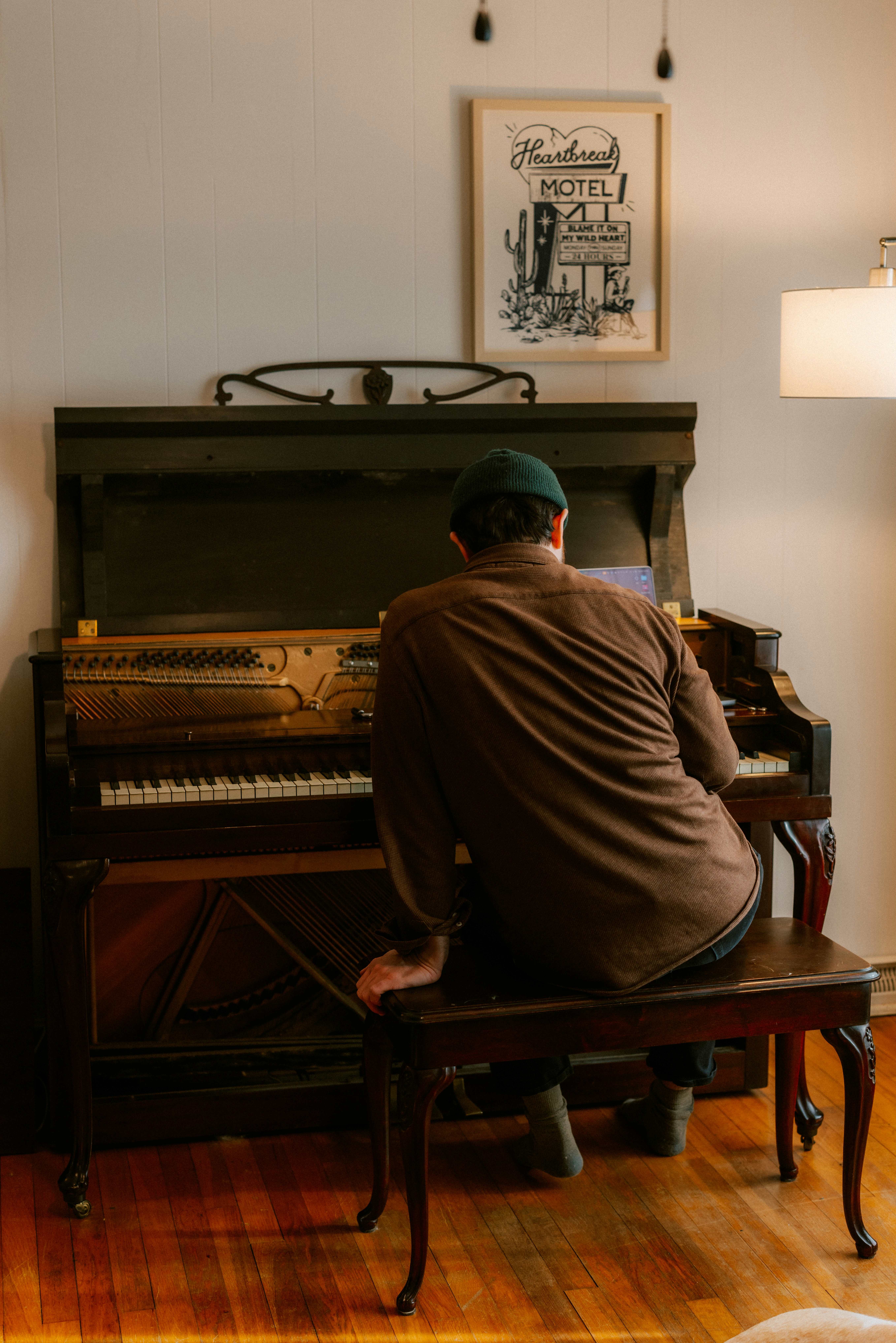 Man playing an old upright piano indoors.