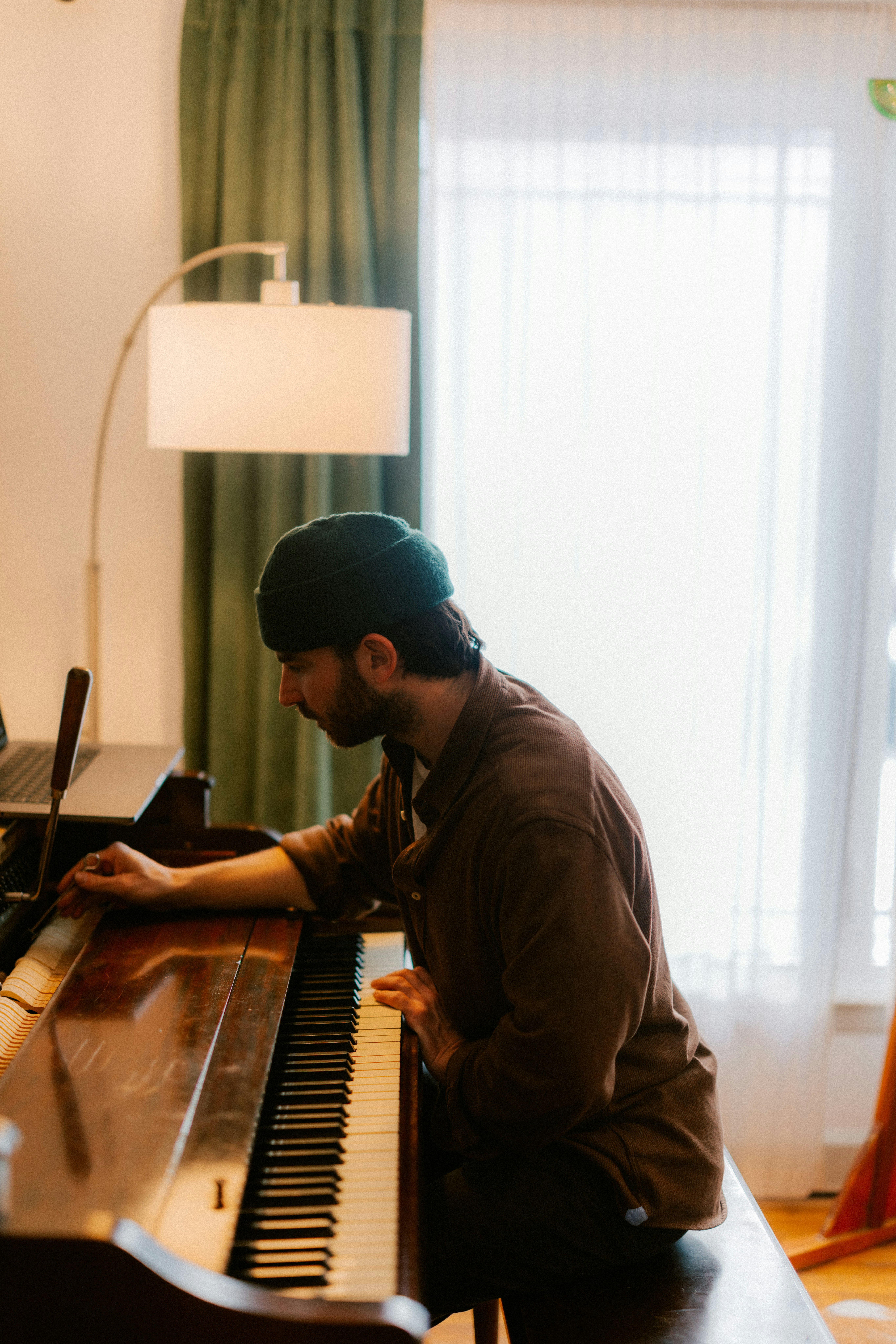 Man in beanie playing a piano indoors