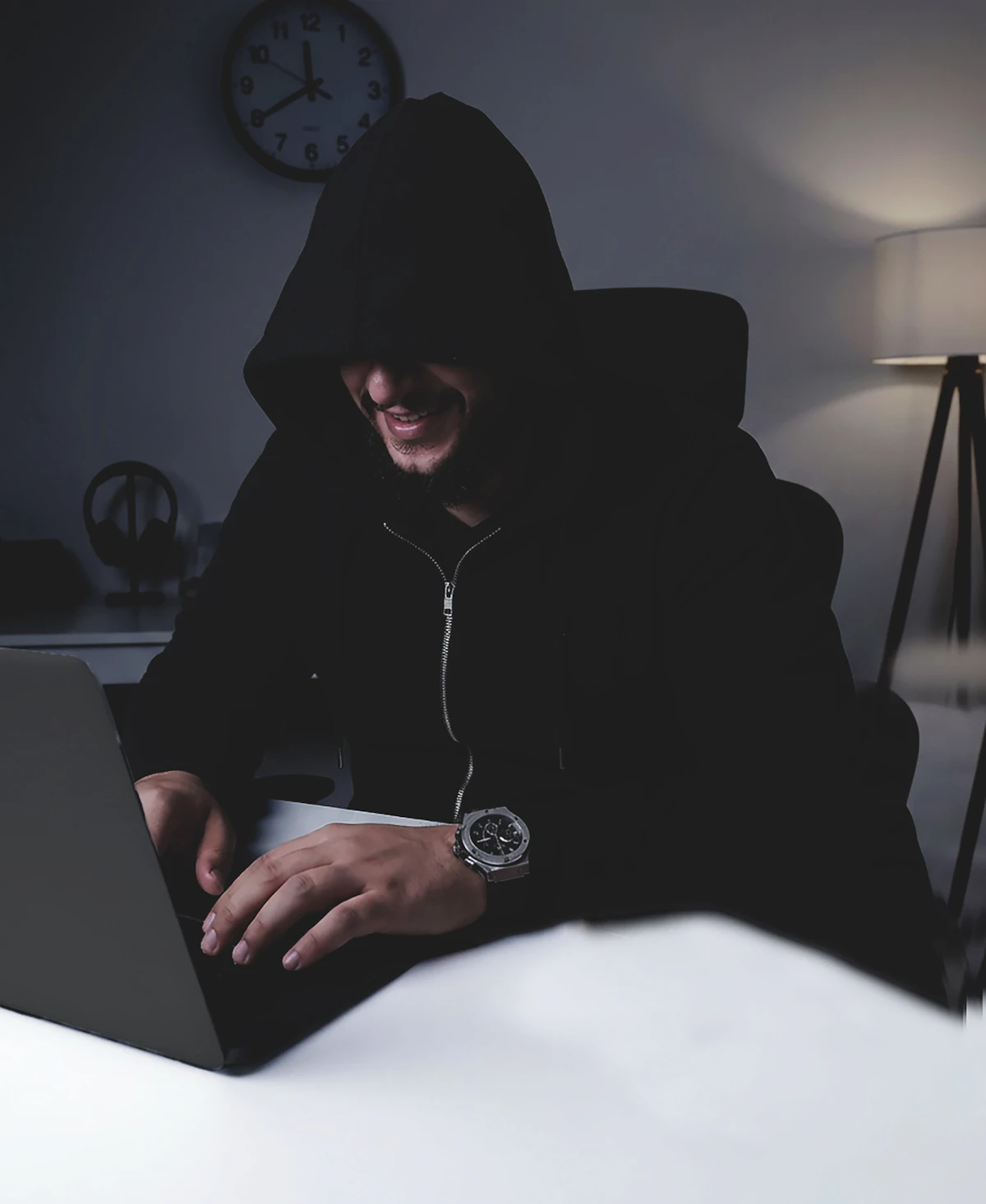 Homem de capuz digitando em notebook à noite