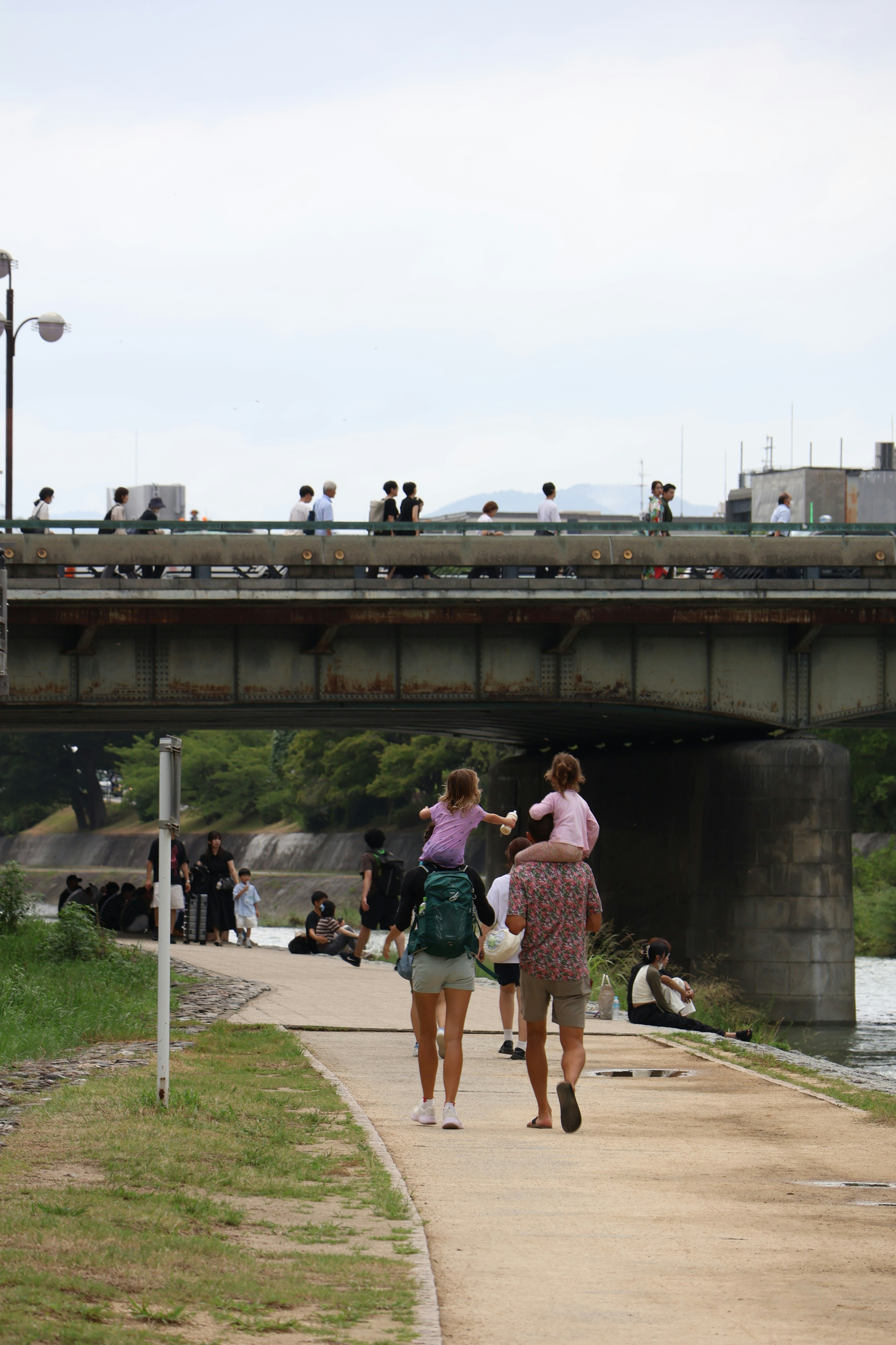 Family walks along a path with children on shoulders.