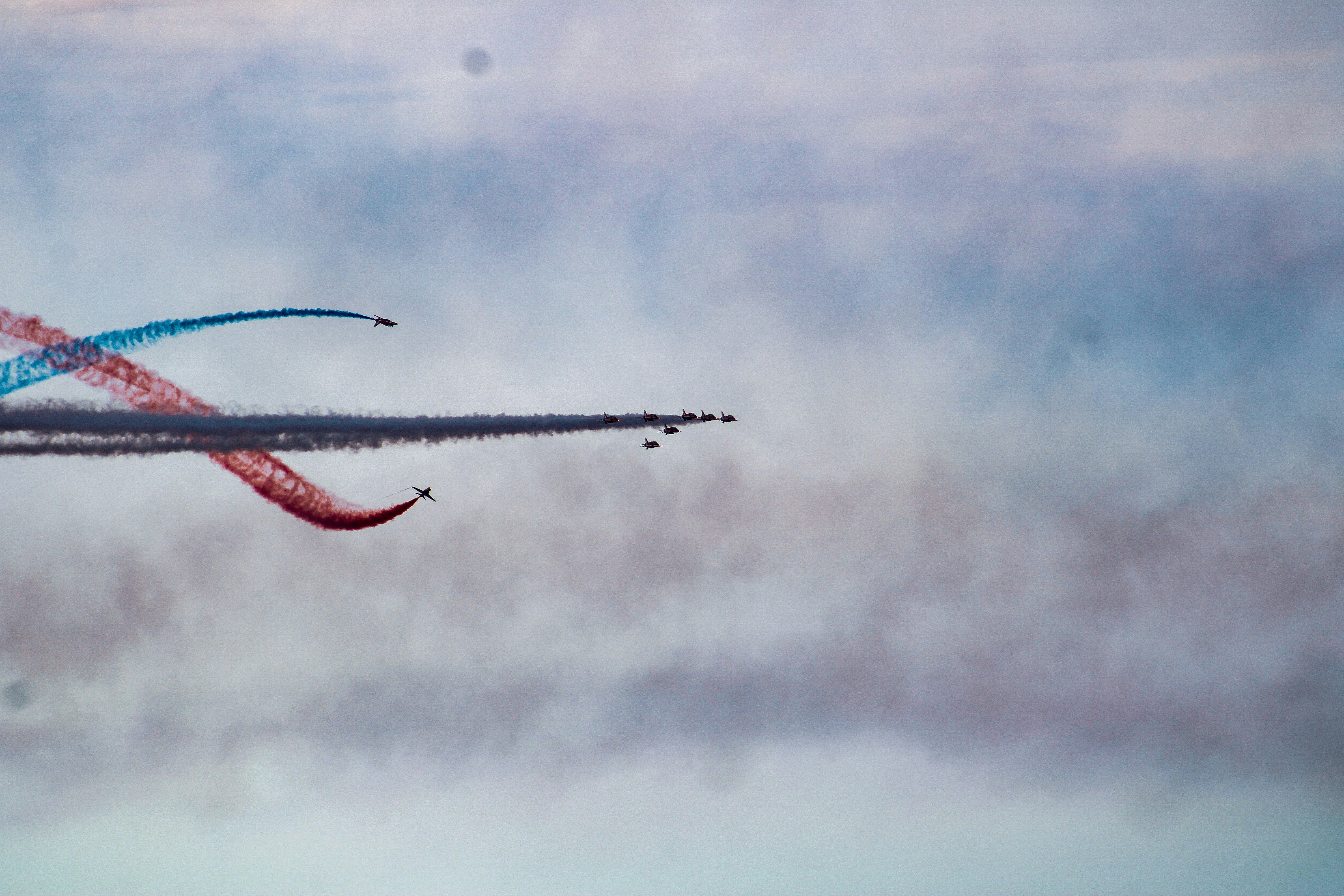 Airplanes performing aerobatics with red and blue smoke trails