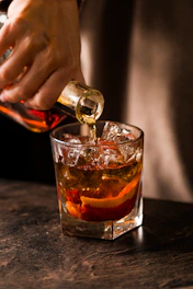 Bartender pouring amber liquid into a glass with ice