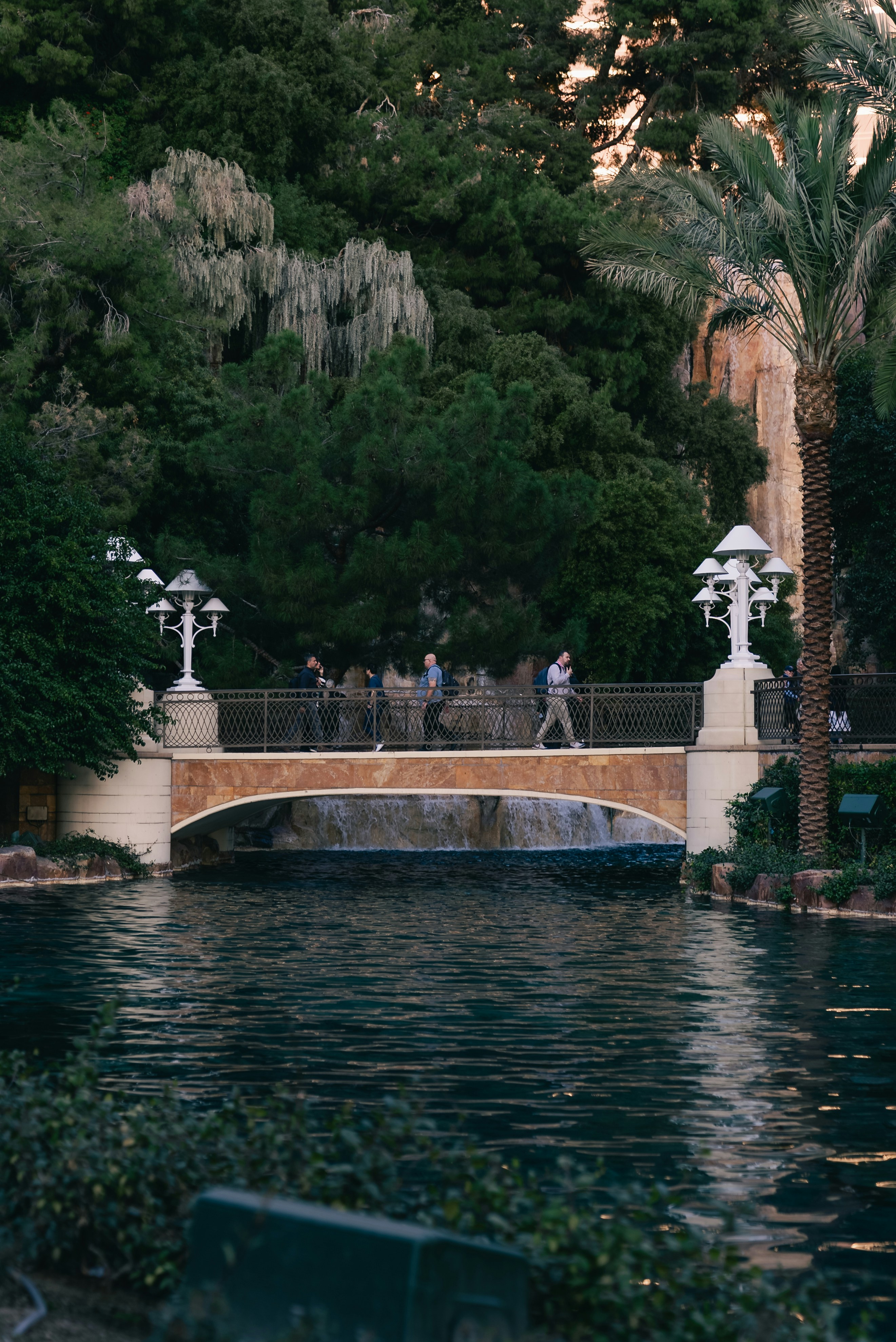 People crossing a bridge over a tranquil body of water.