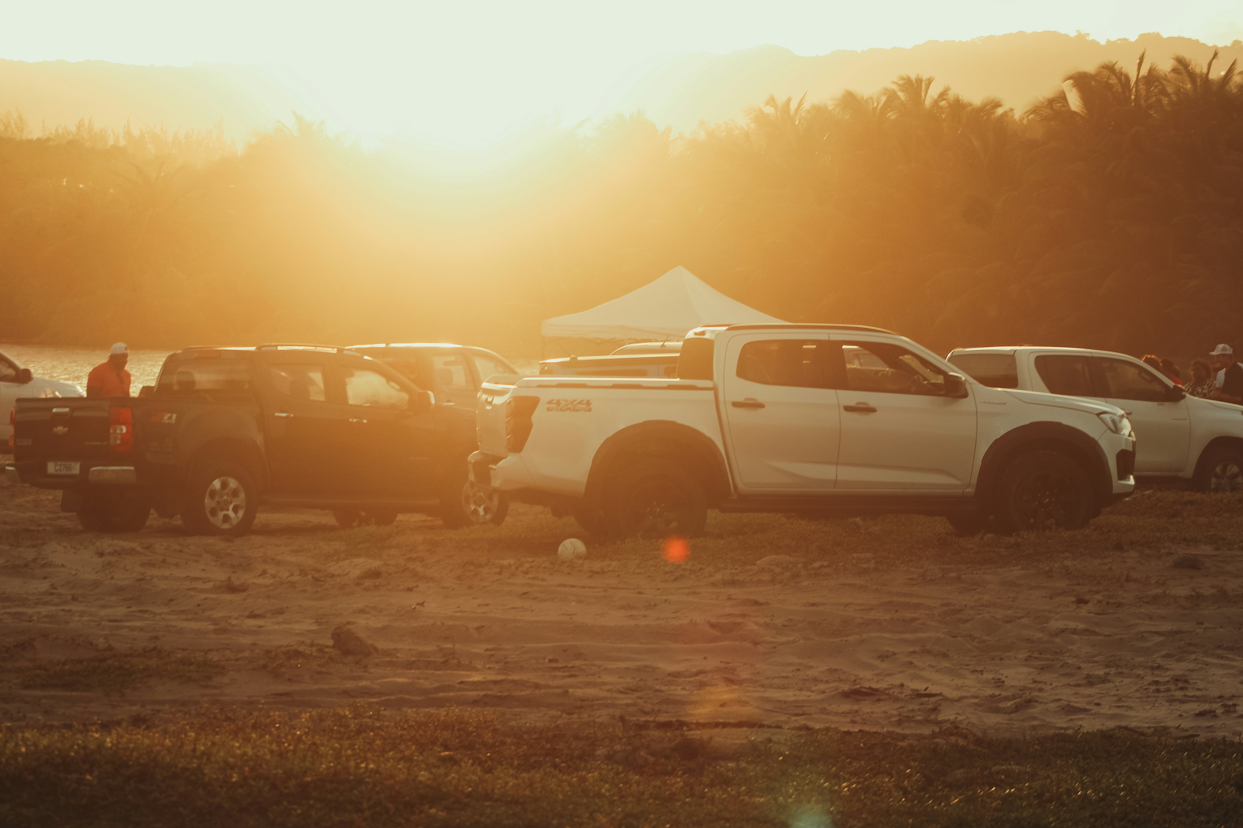 Pickup trucks parked on a beach at sunset