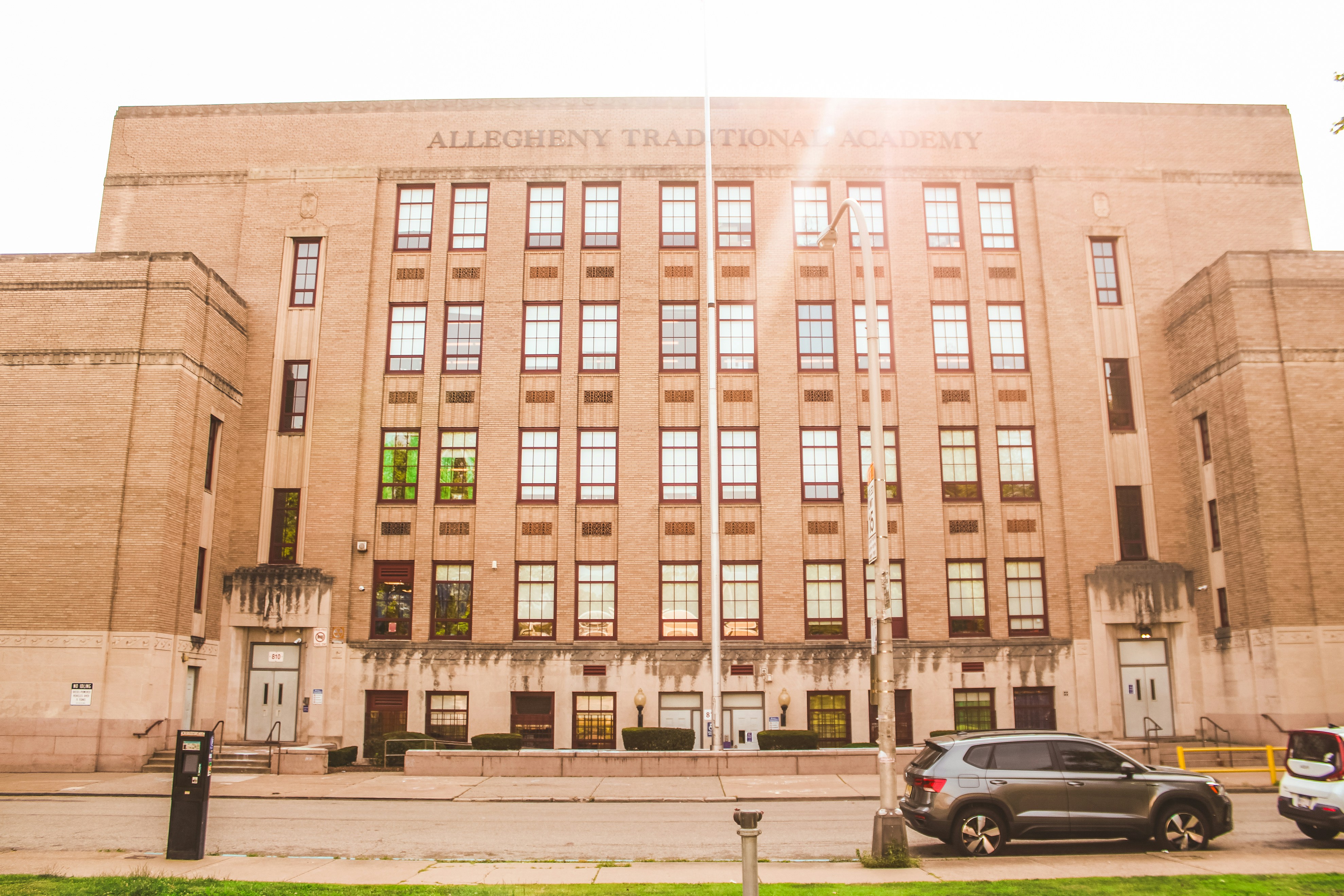 Large brick building with many windows and parked cars