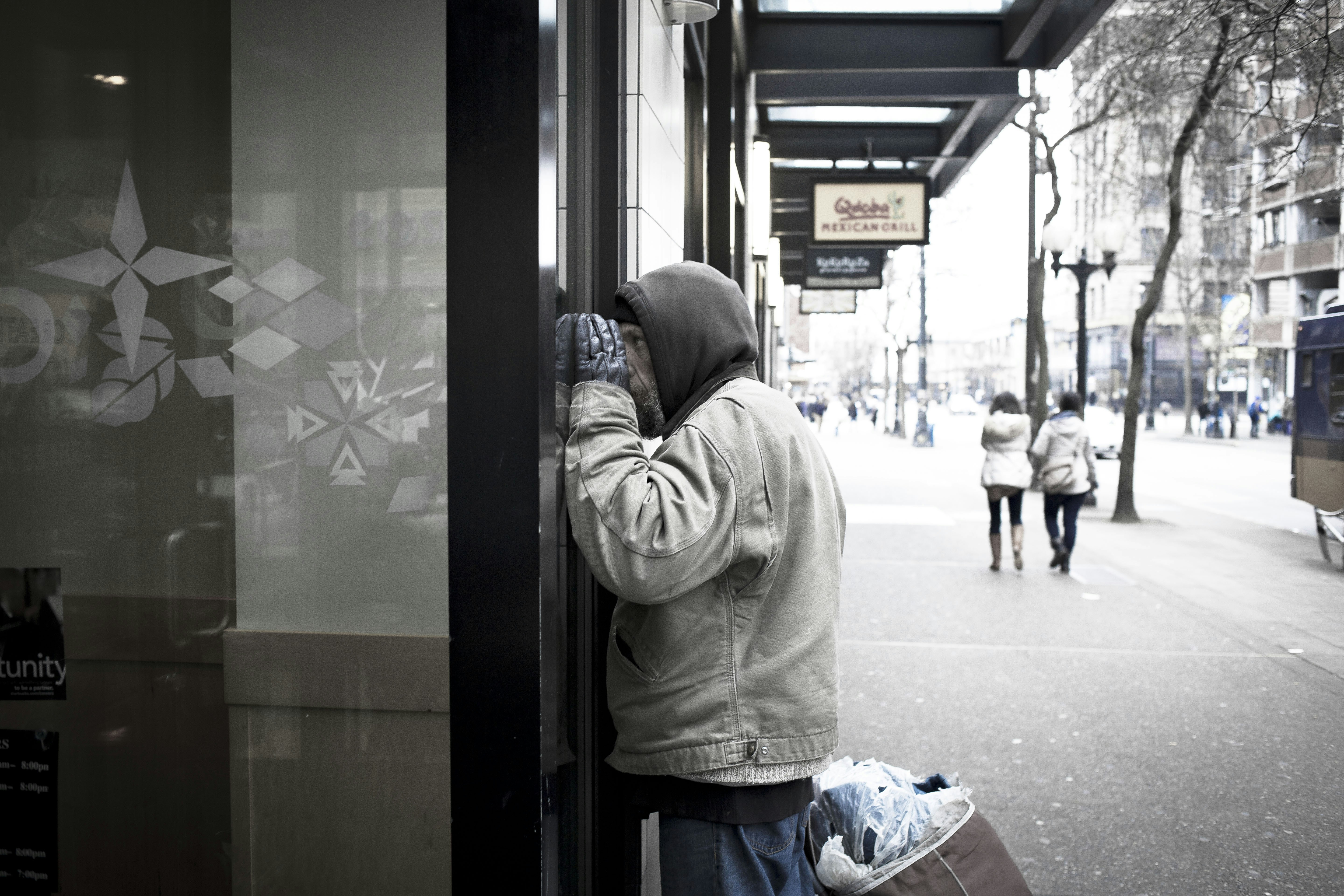 Man peeking into a storefront window on a street.