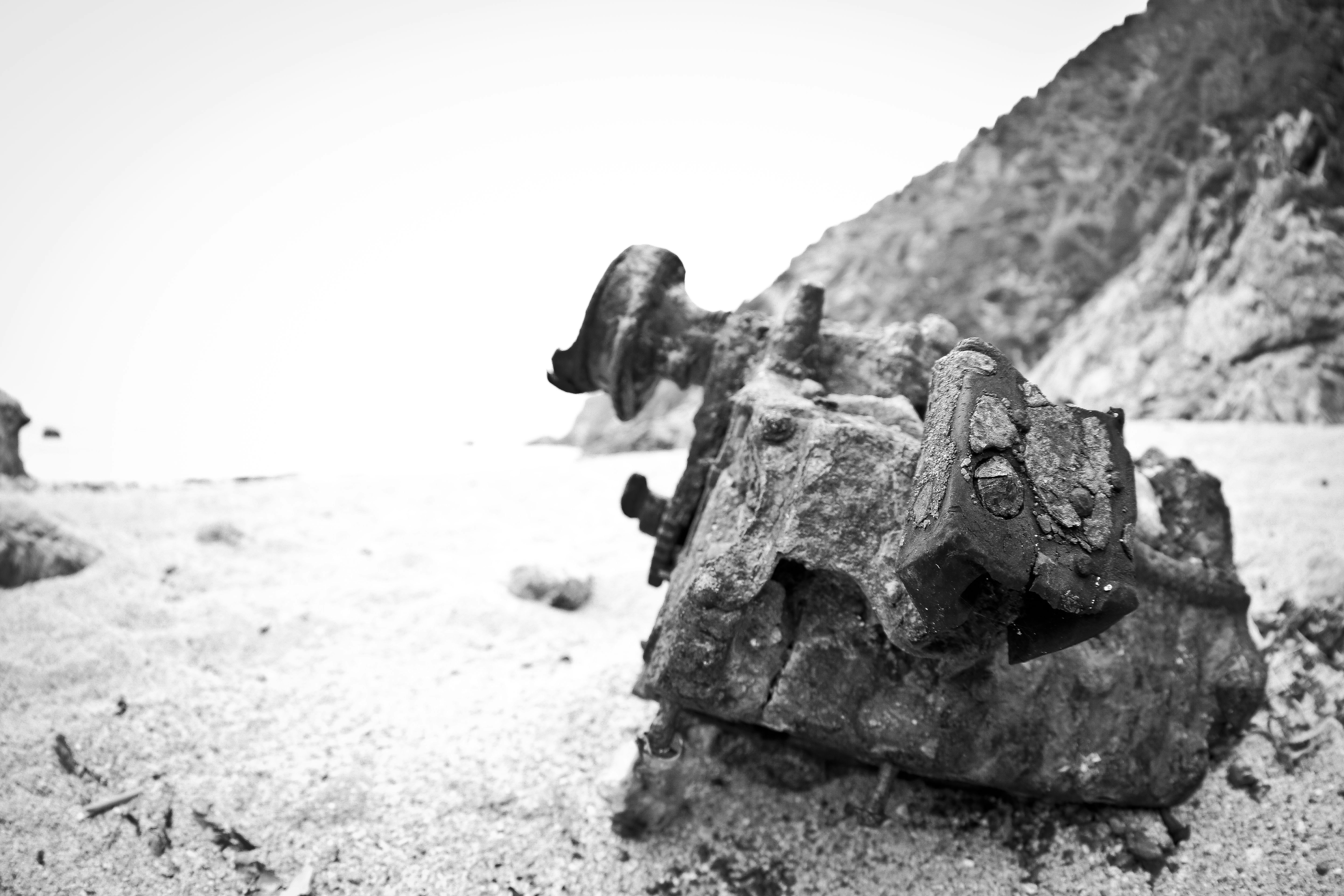 Rusted machinery rests on a sandy beach.