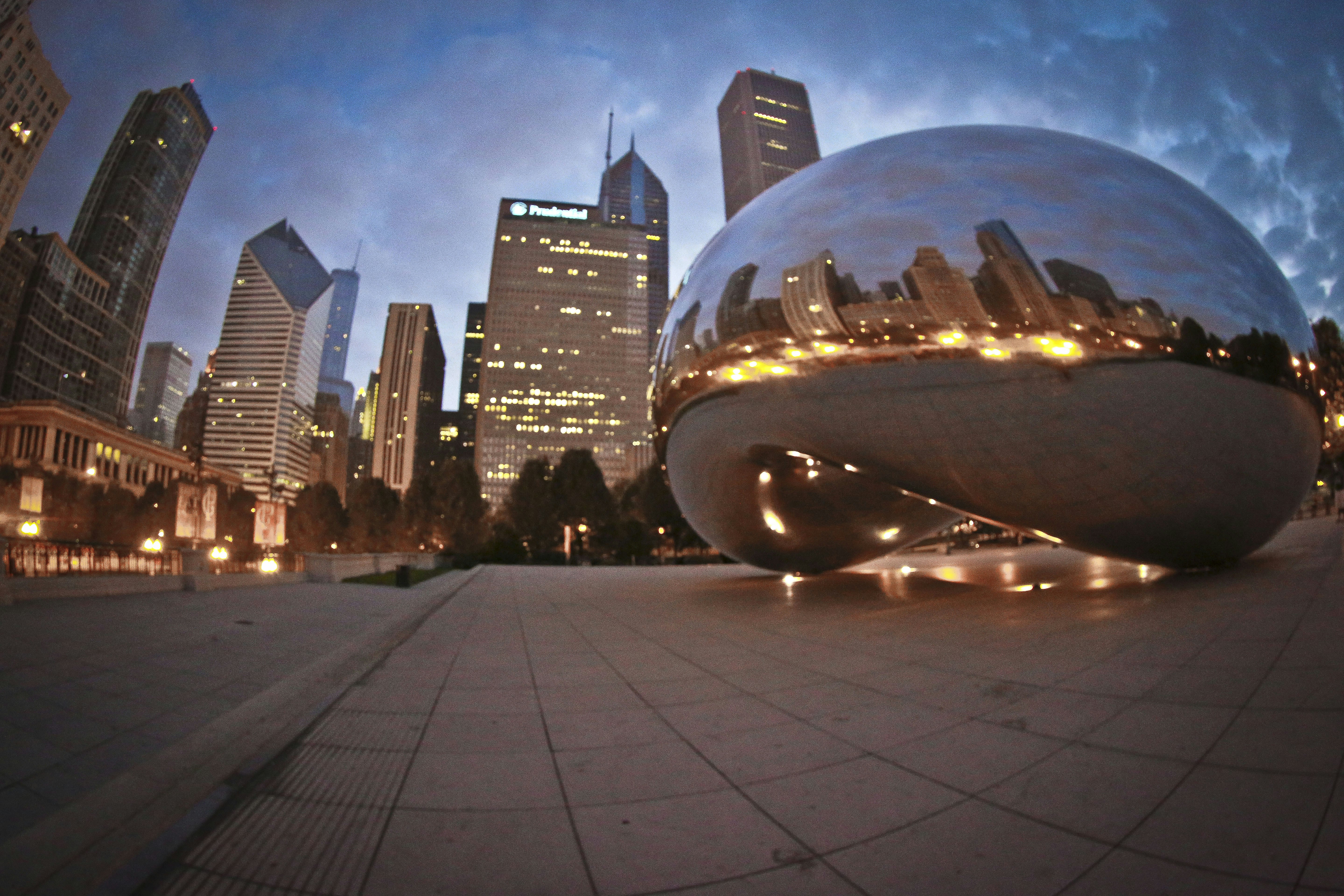 Cloud gate sculpture reflects city skyline at dusk
