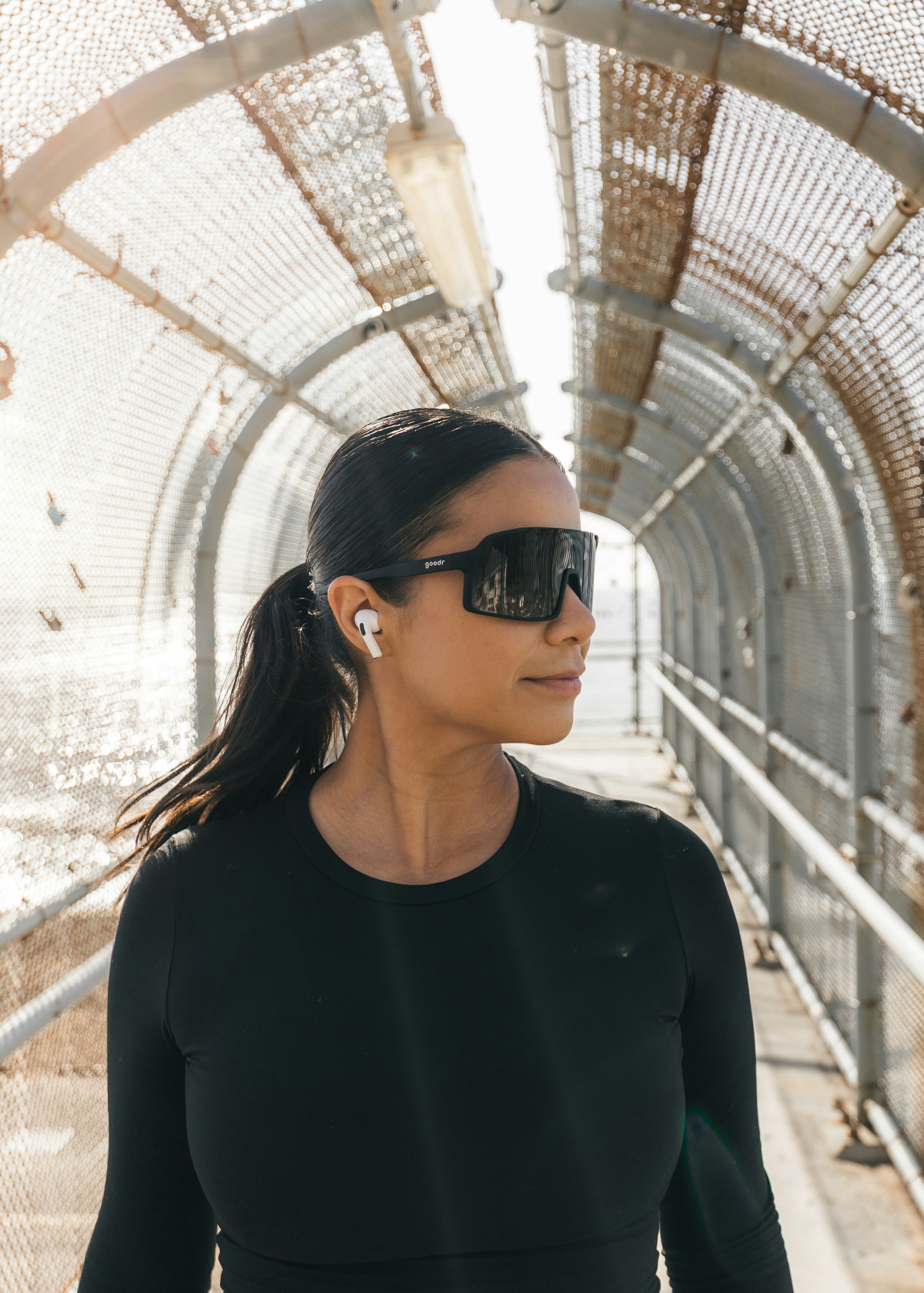 Femme portant des lunettes de soleil et des écouteurs sur une passerelle