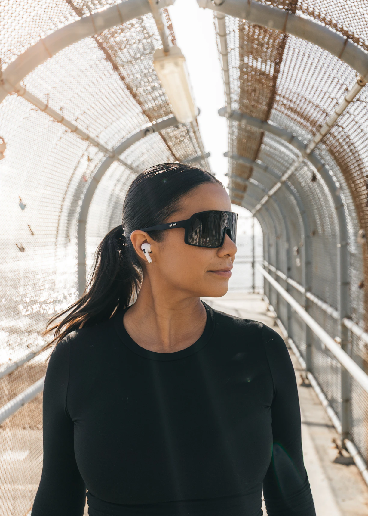 Woman wearing sunglasses and earbuds on a walkway