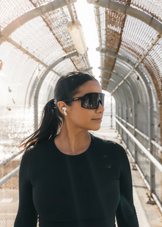 Woman wearing sunglasses and earbuds on a walkway