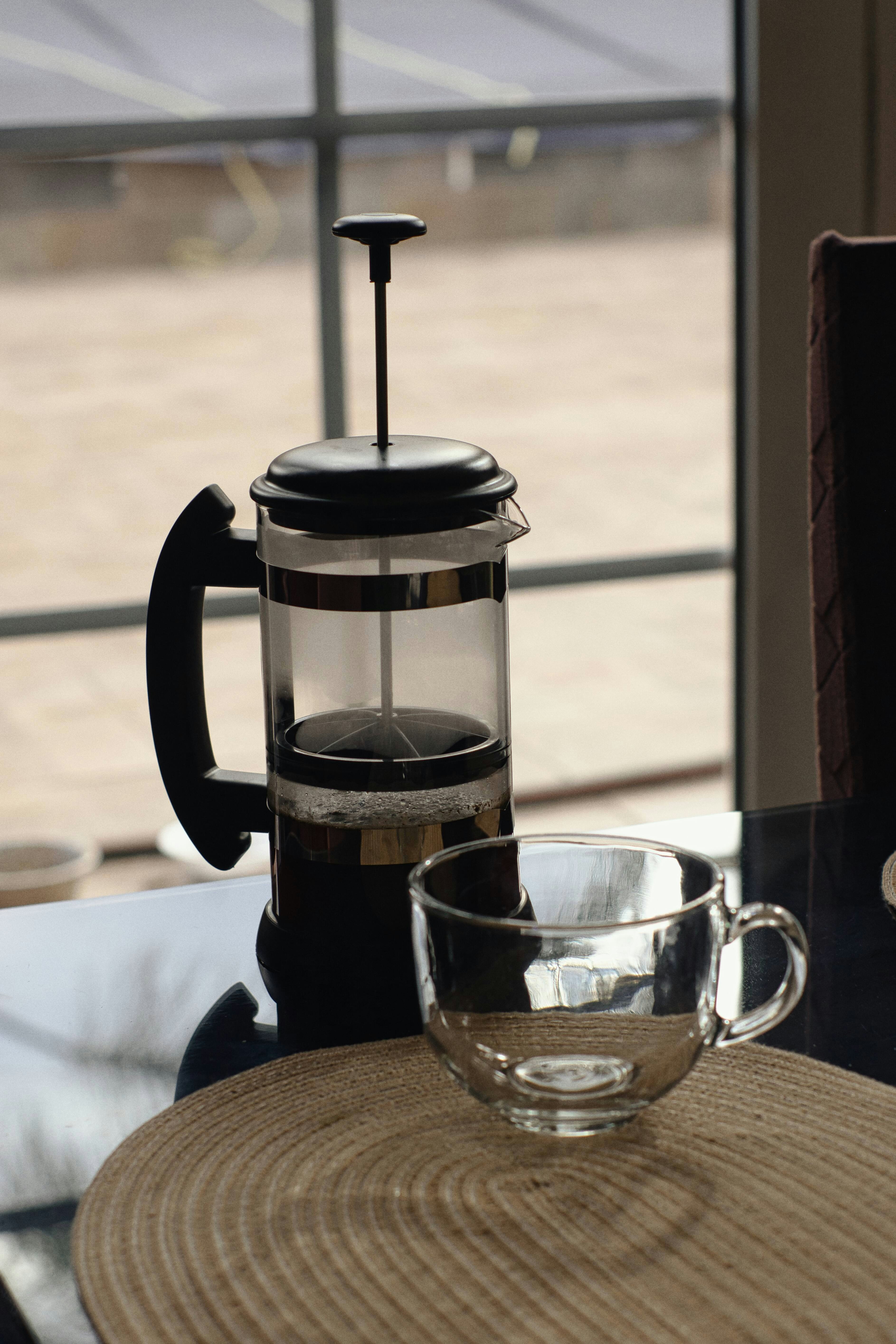 French press and empty glass cup on table.