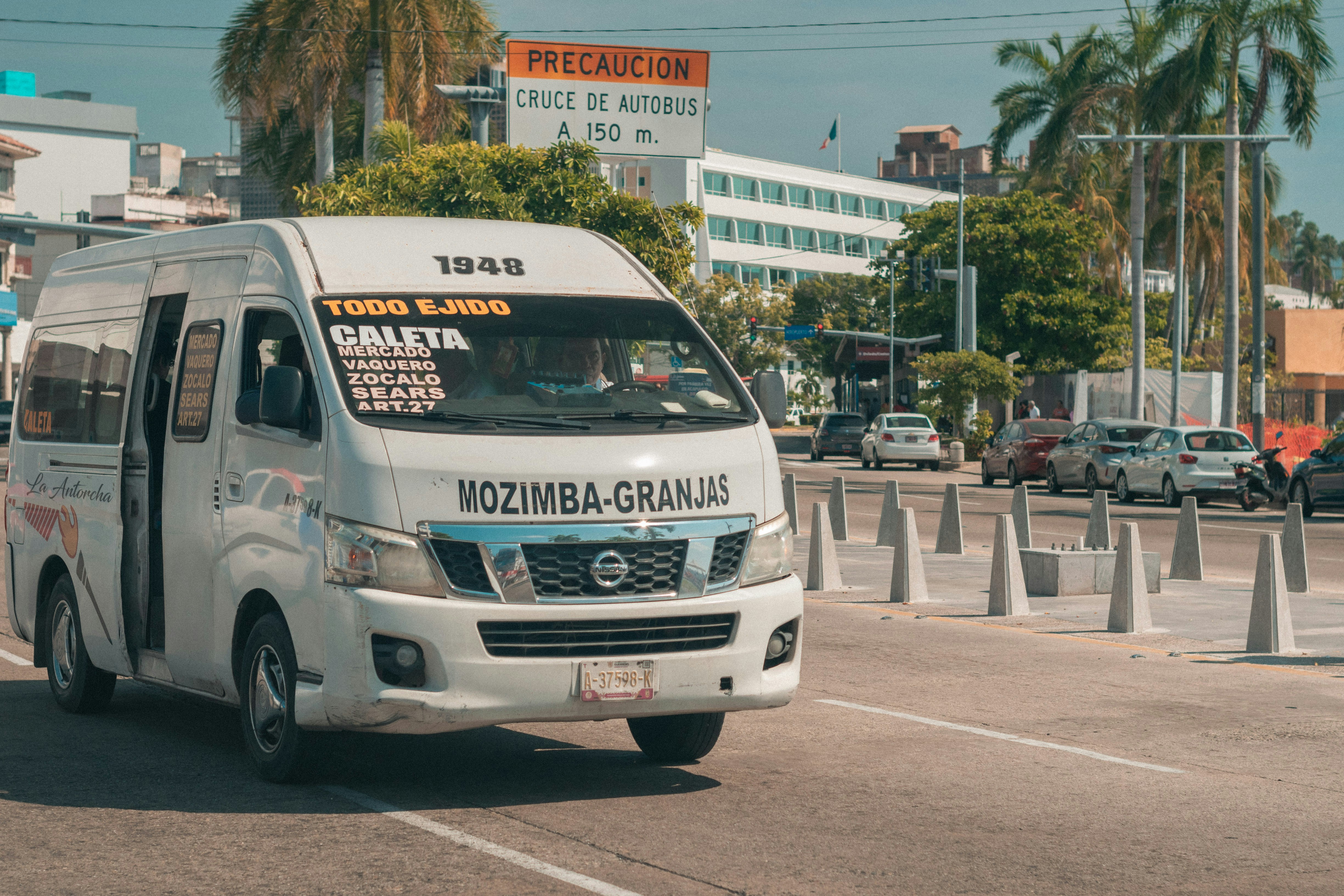 A white passenger van driving on a street.