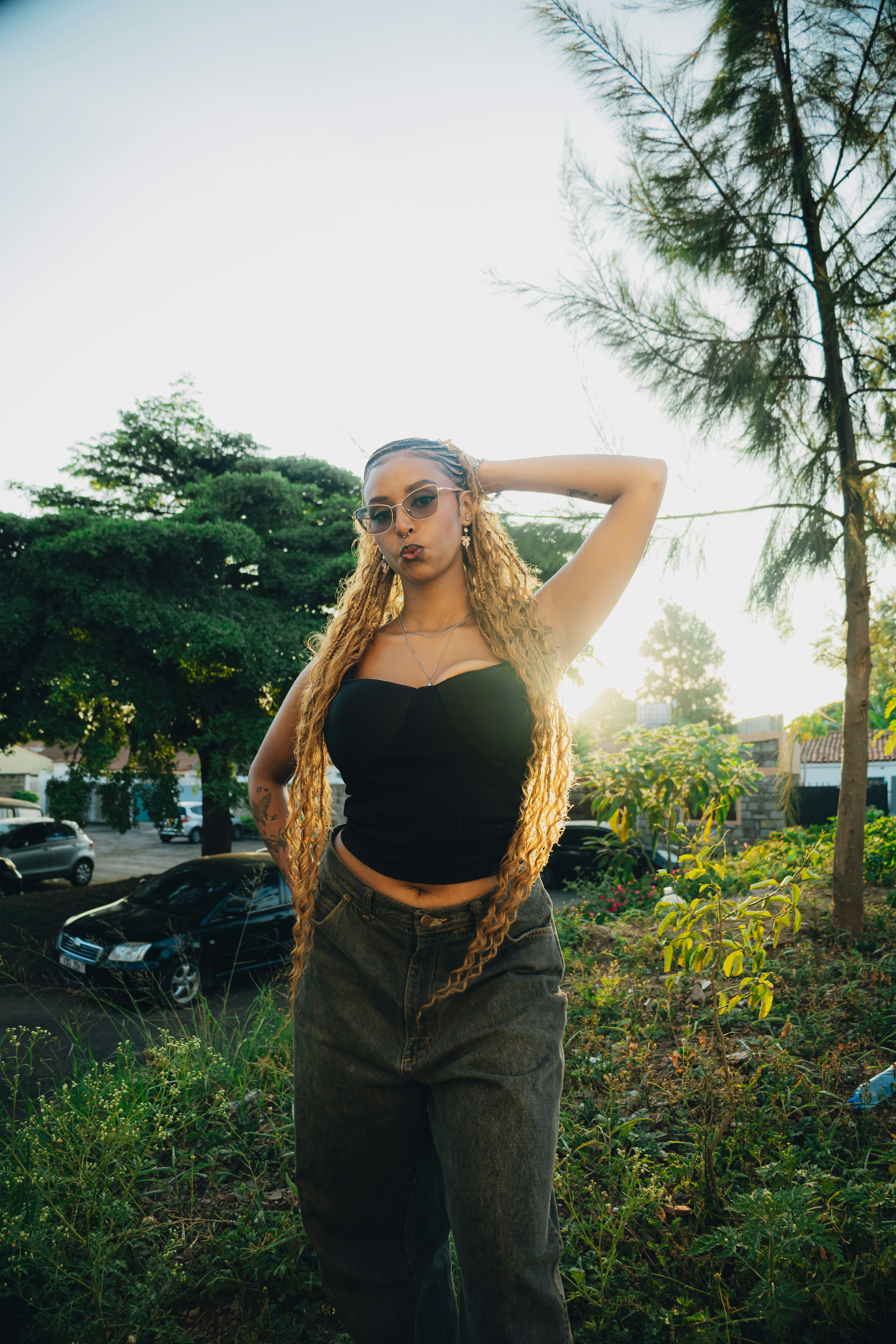 A young woman with long blonde braids poses outdoors.