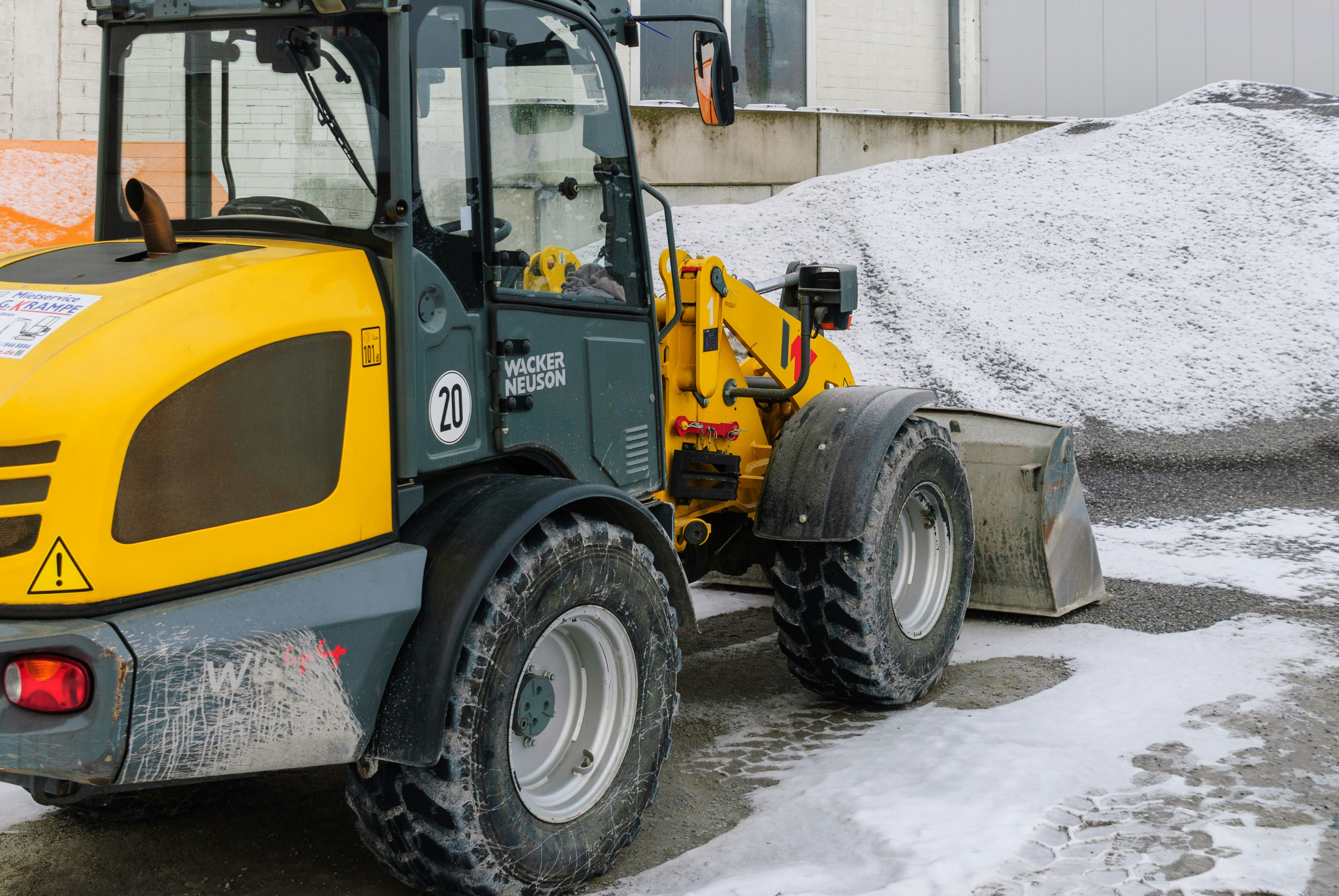 Yellow front loader moving snow