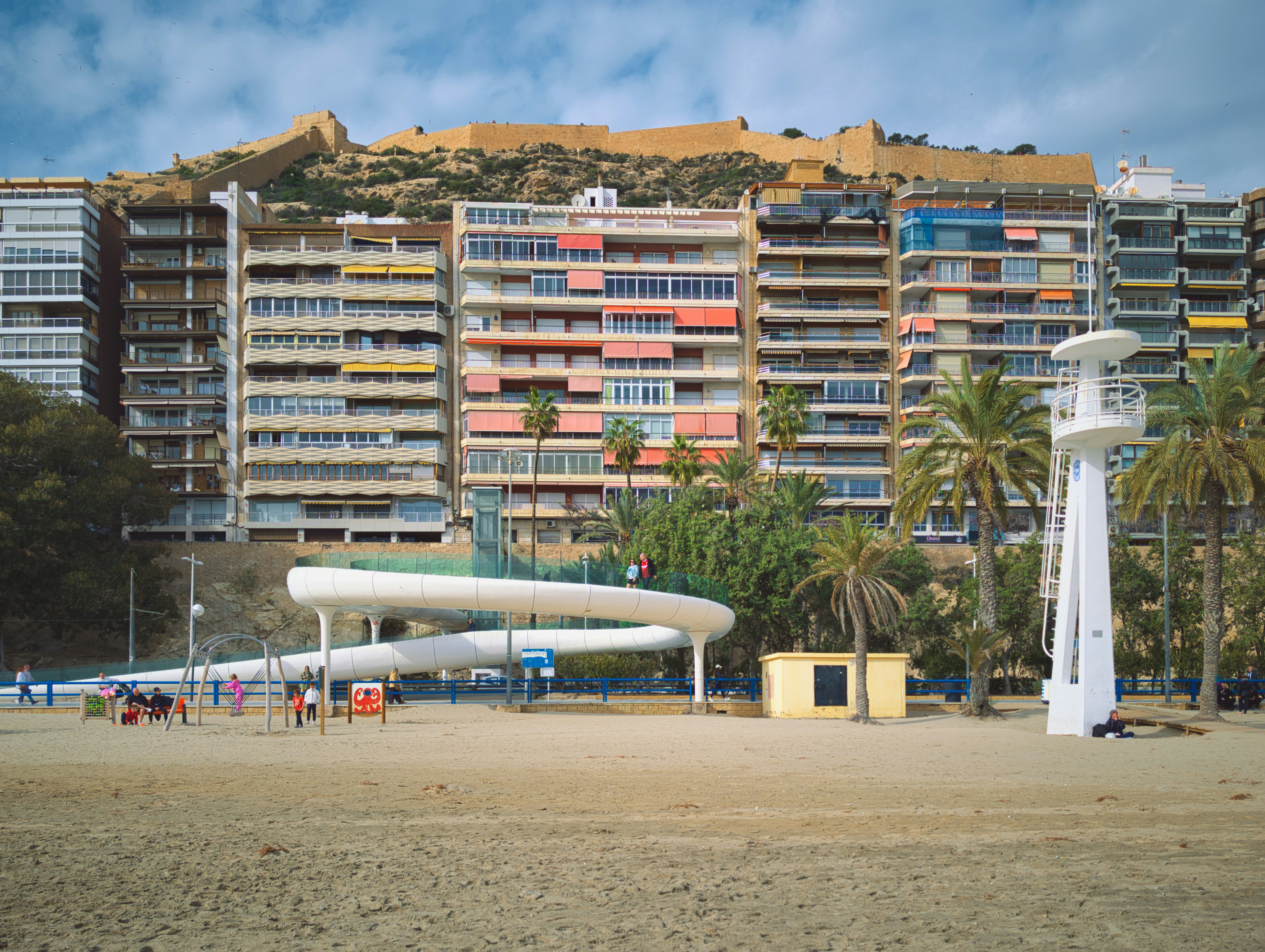 Beach with colorful buildings and a castle on hill.