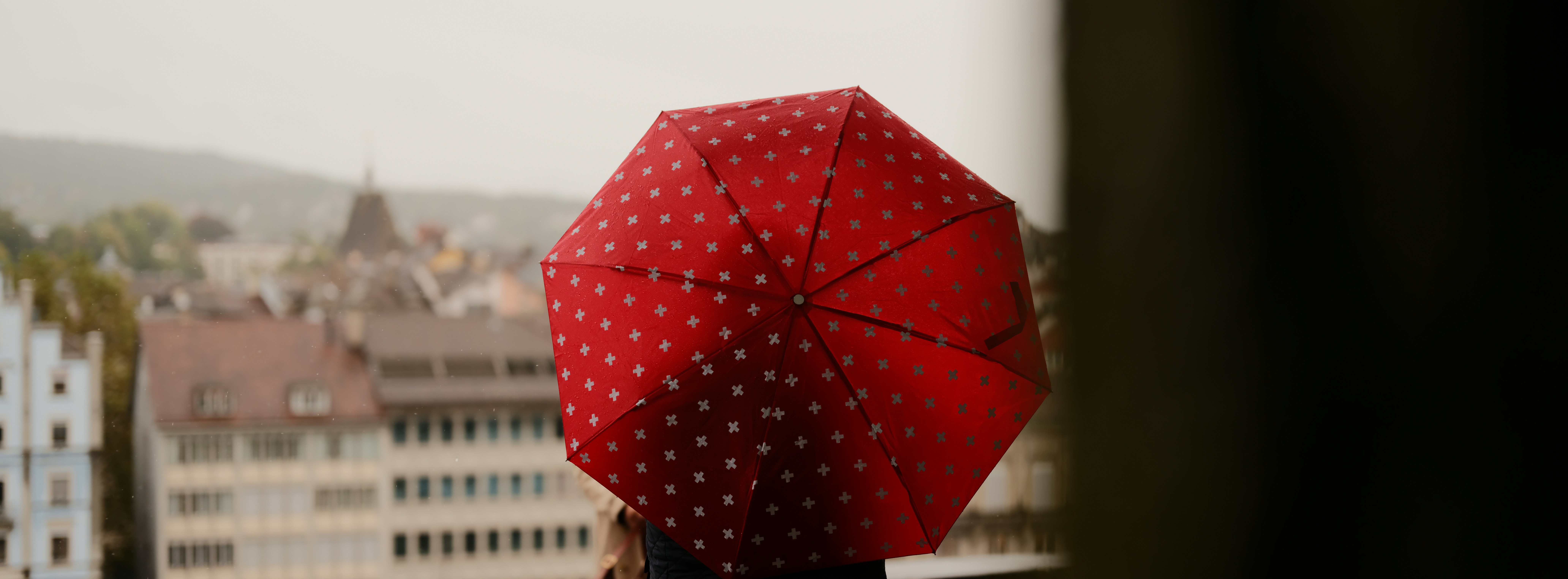 Red polka dot umbrella against a city skyline