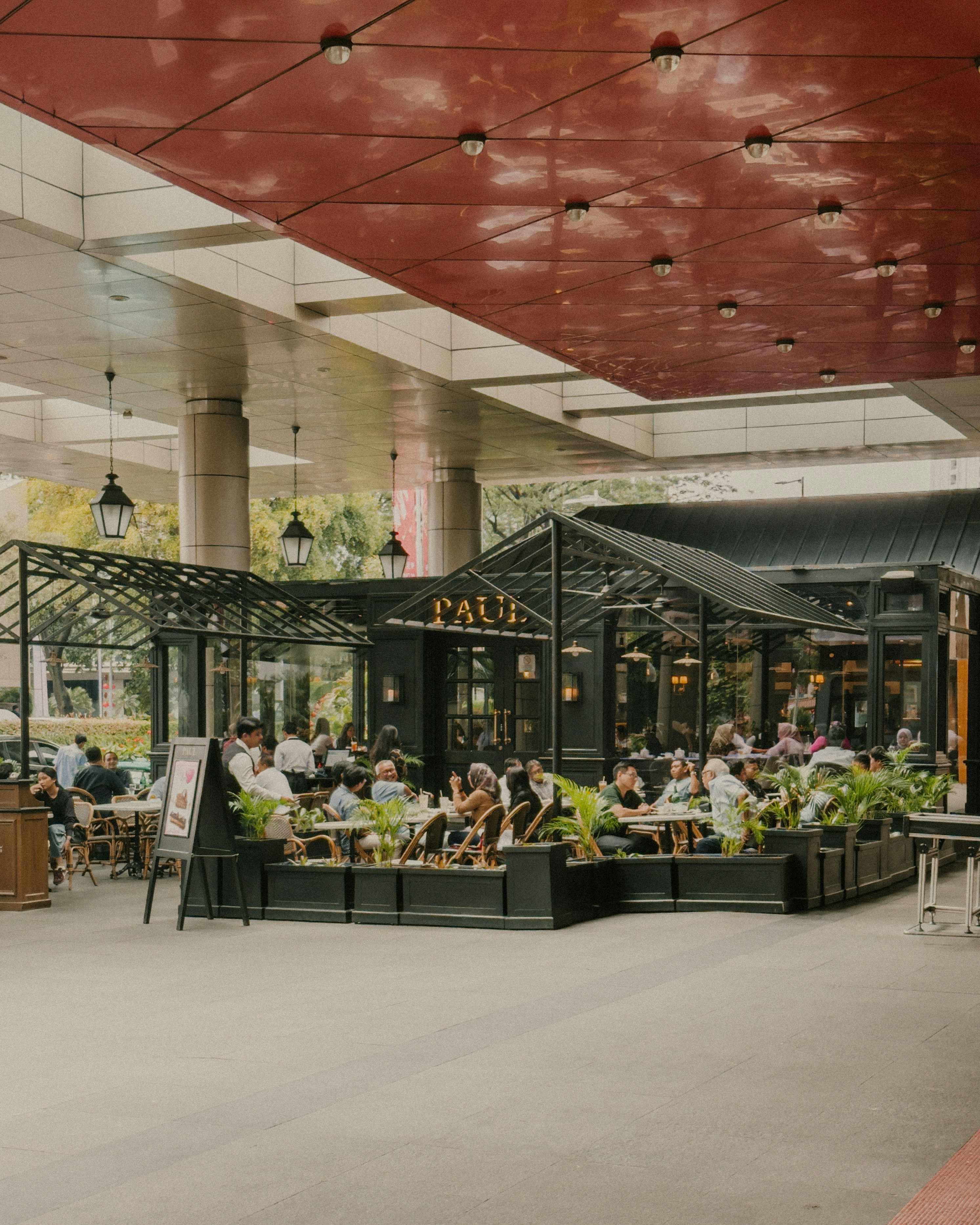 Leute, die in einem Außencafé mit Glaswänden essen.