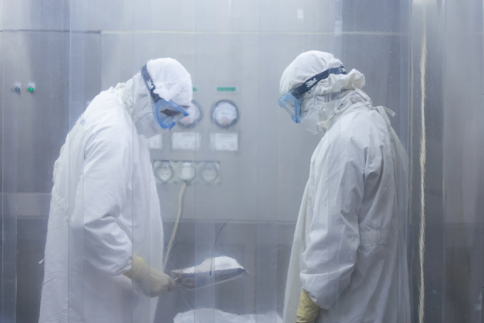 Two scientists in protective suits working in a life sciences cleanroom facility