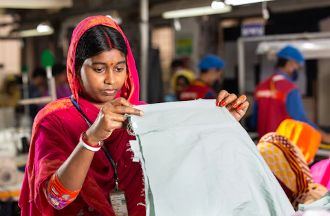 A textile worker holding up fabric to inspect it — representative image