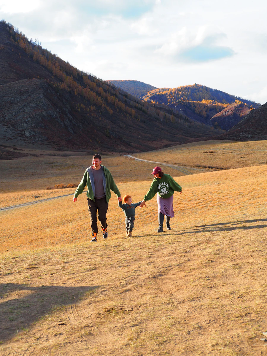 Family walking hand in hand across a grassy hill