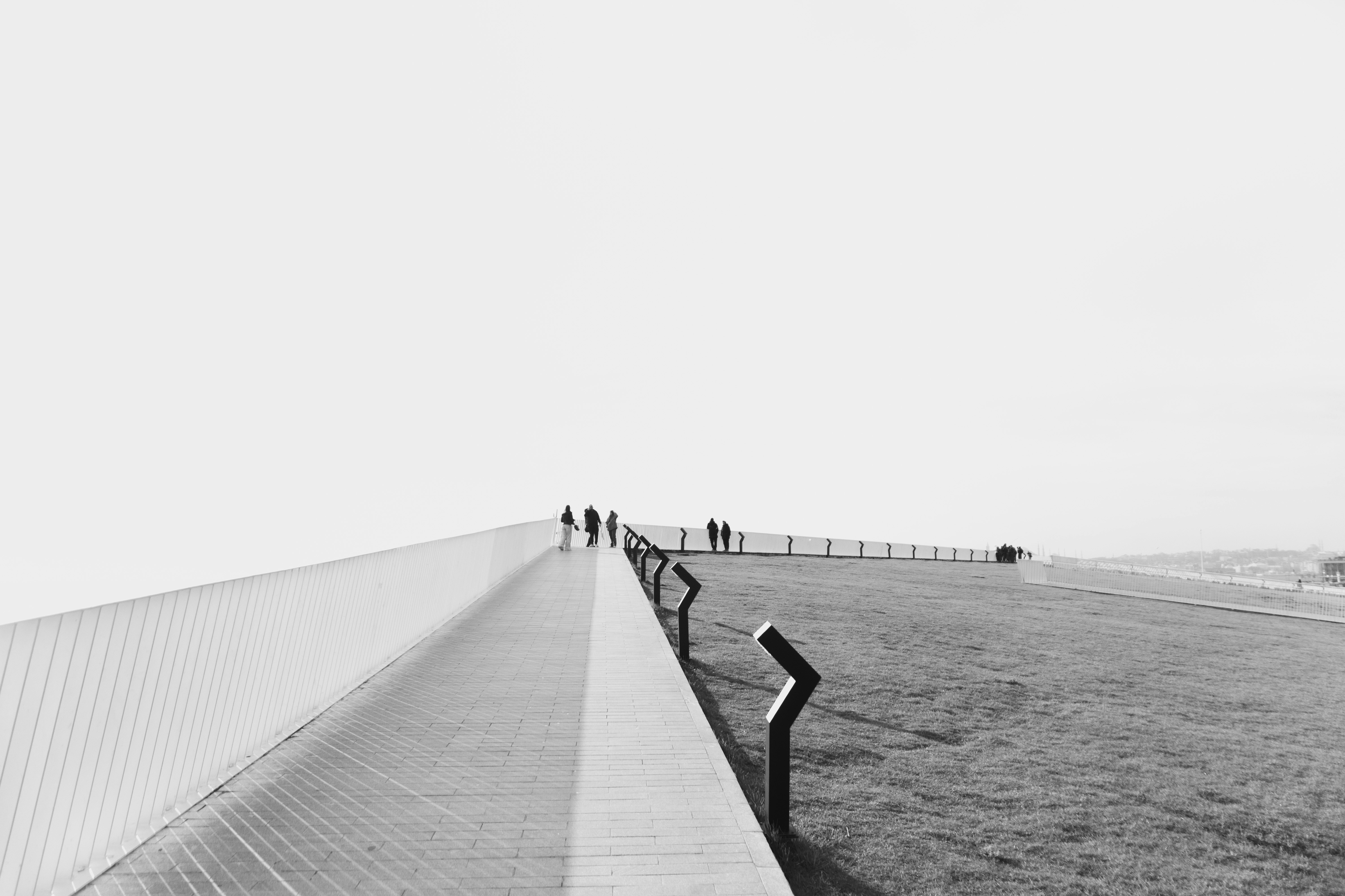 People walking on a modern pathway with grassy area.