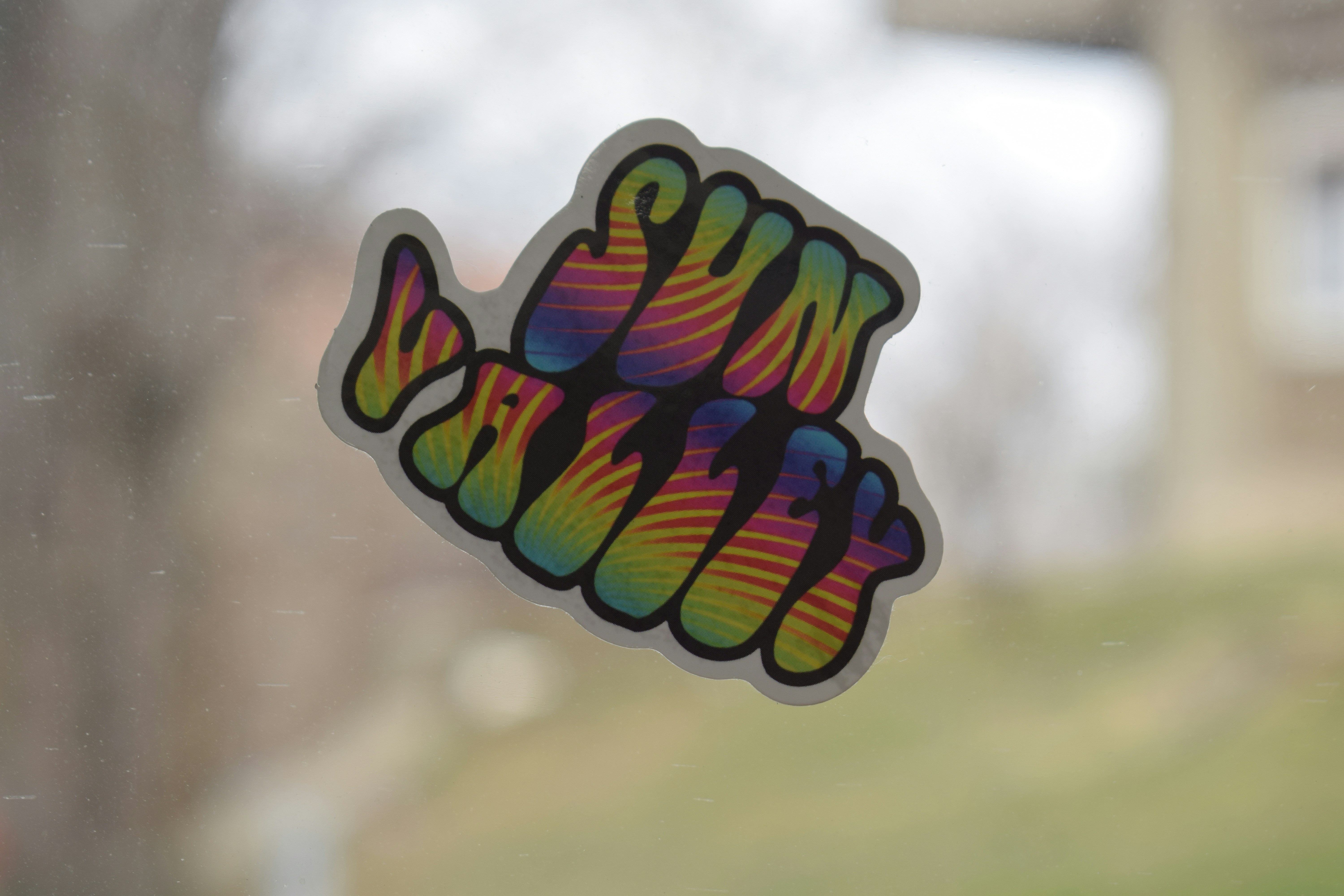 Rainbow sticker with wavy lettering on glass