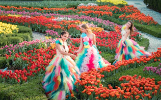 Three women in colorful dresses among vibrant tulip gardens