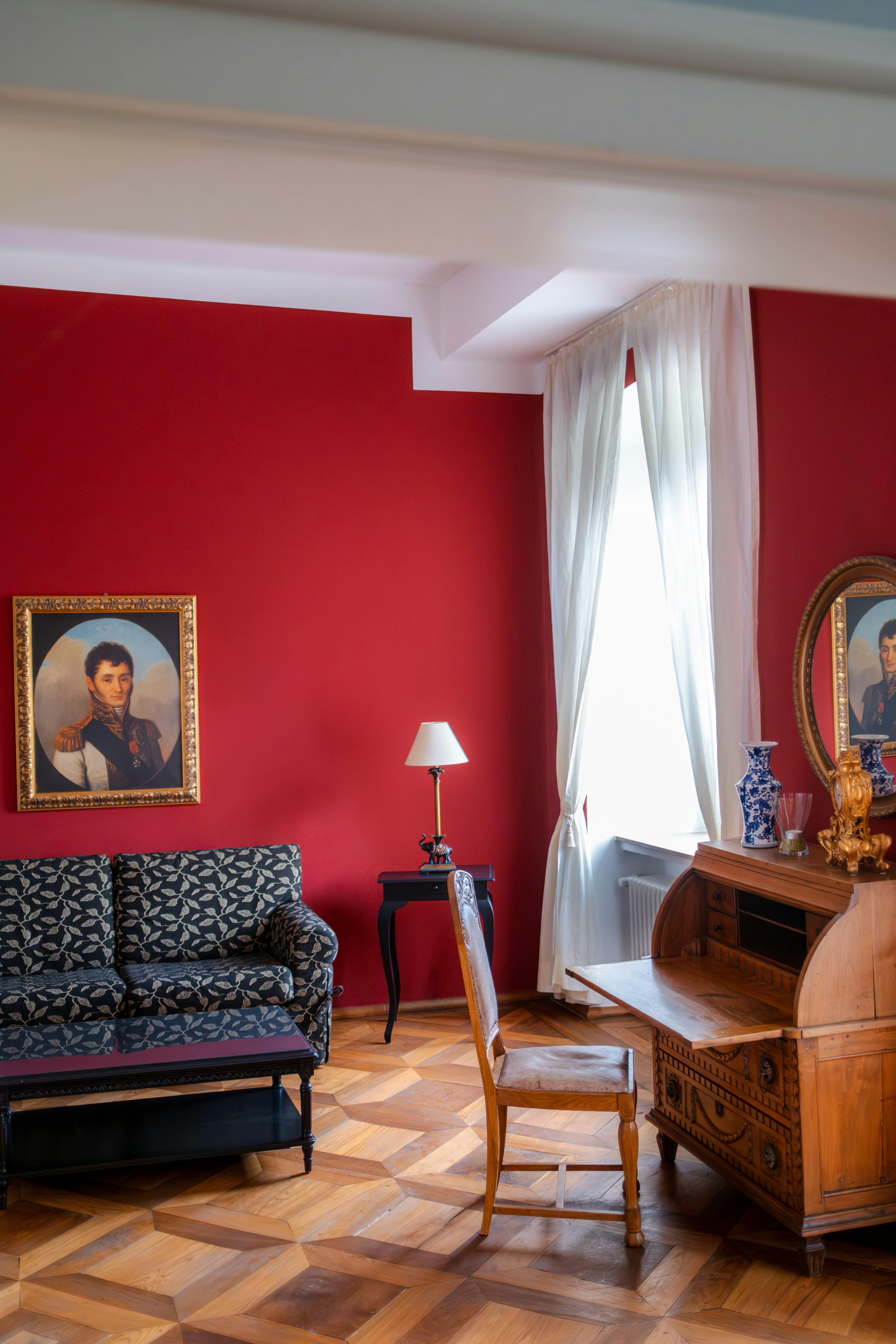 Elegant room with antique desk and red walls.
