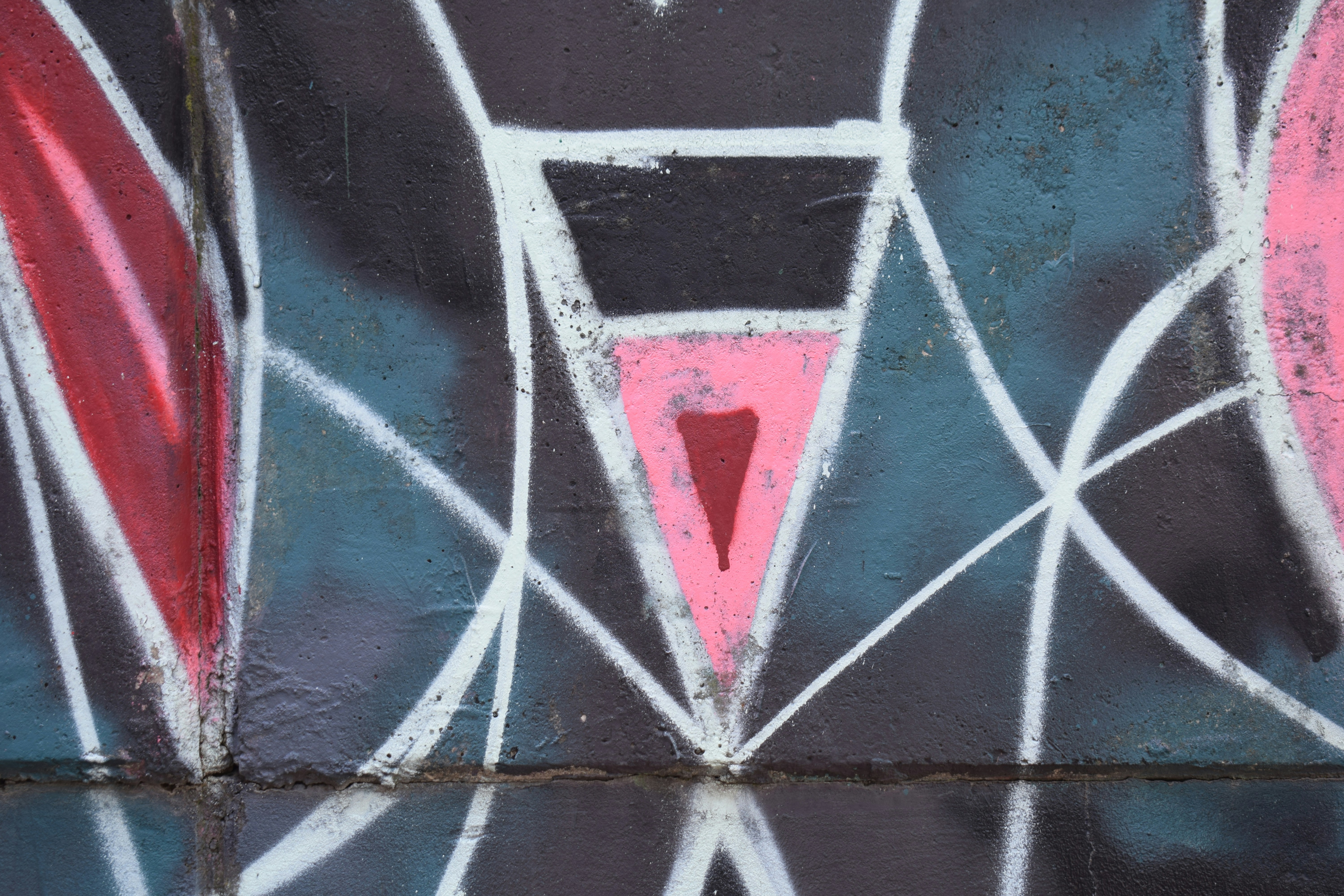 Abstract graffiti with pink and white geometric shapes.