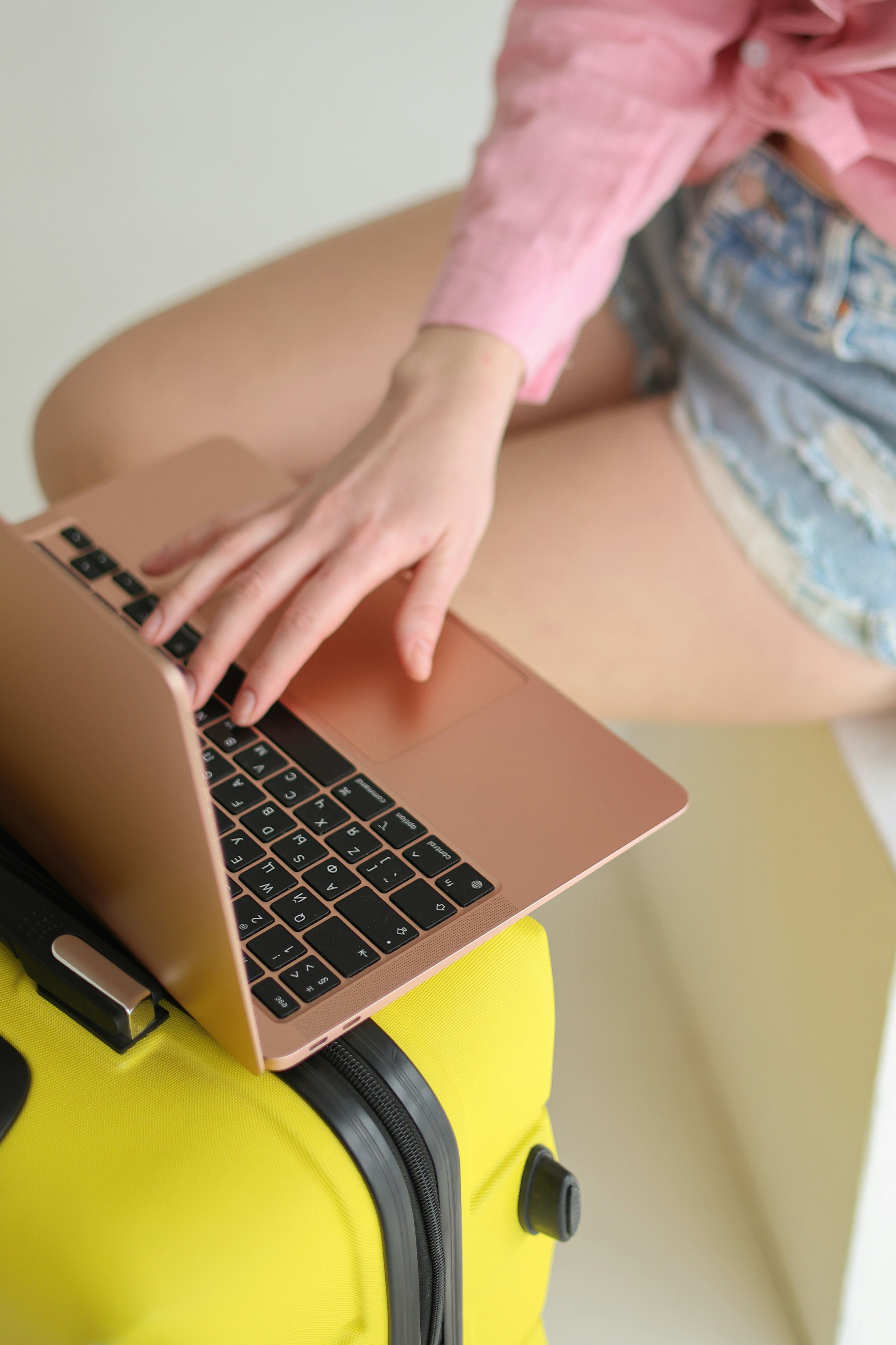Woman using a laptop on a yellow suitcase