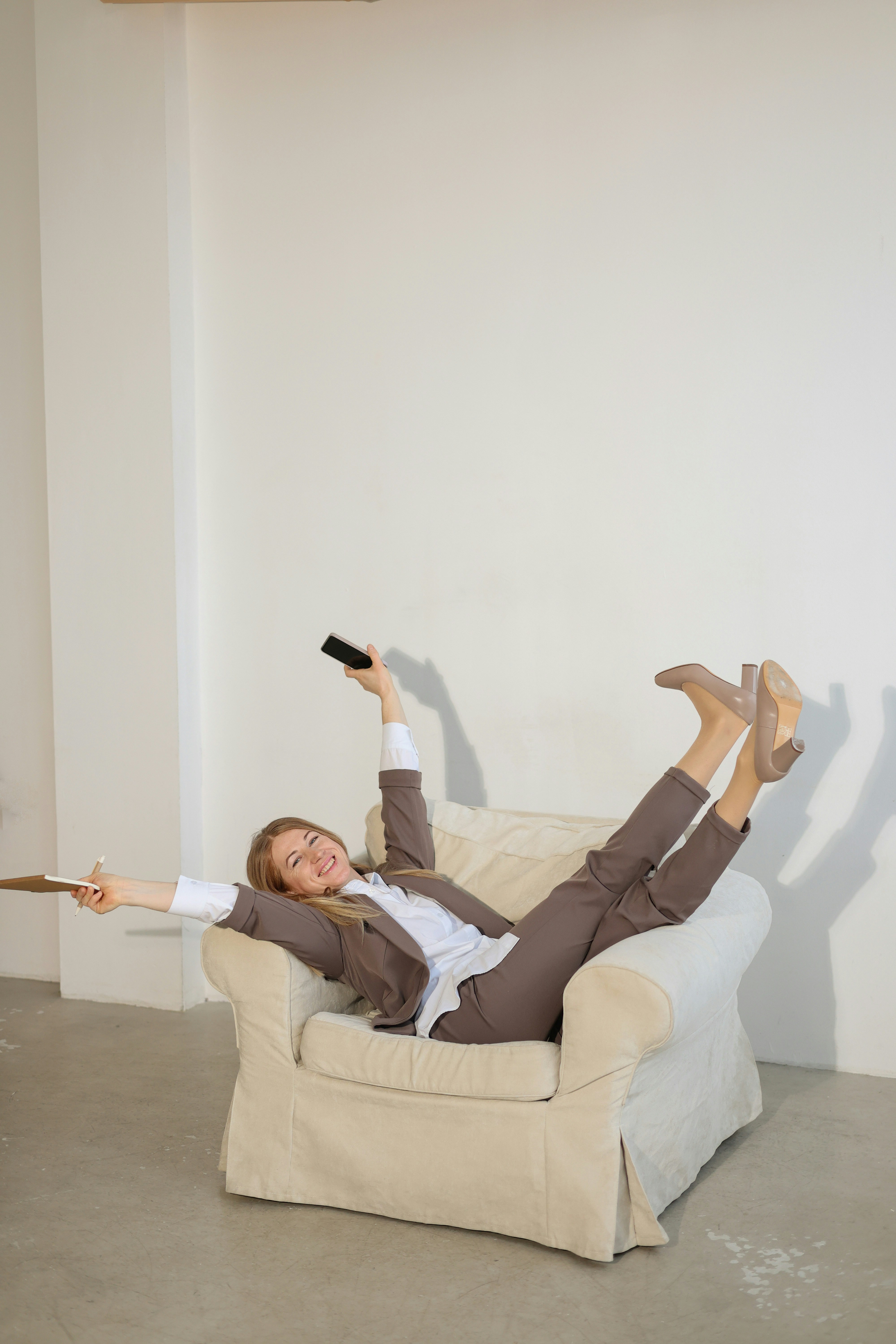 スーツ姿の女性がリモコンでアームチェアでくつろいでいる。