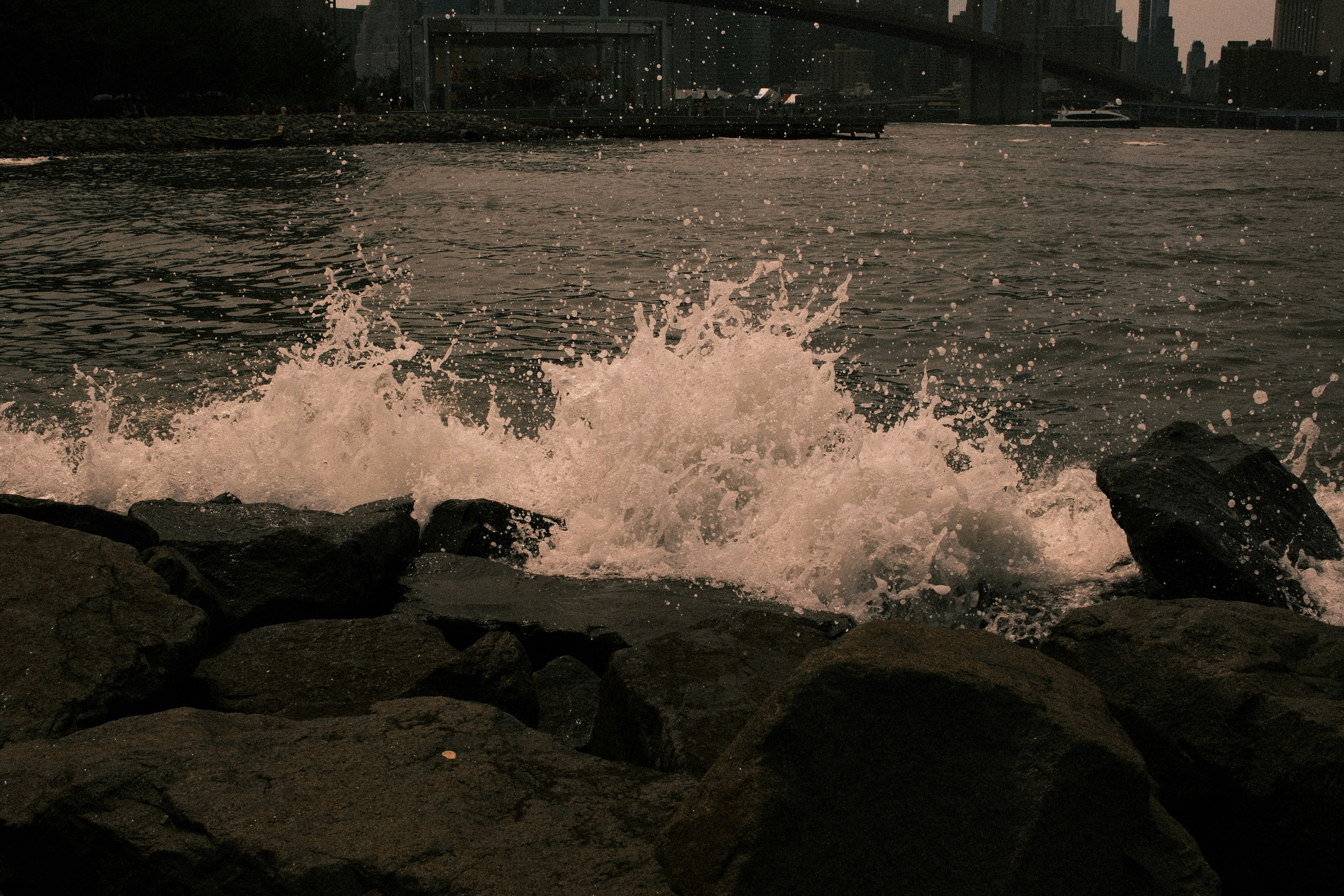 Onde che si infrangono sulle rocce vicino allo skyline di una città.