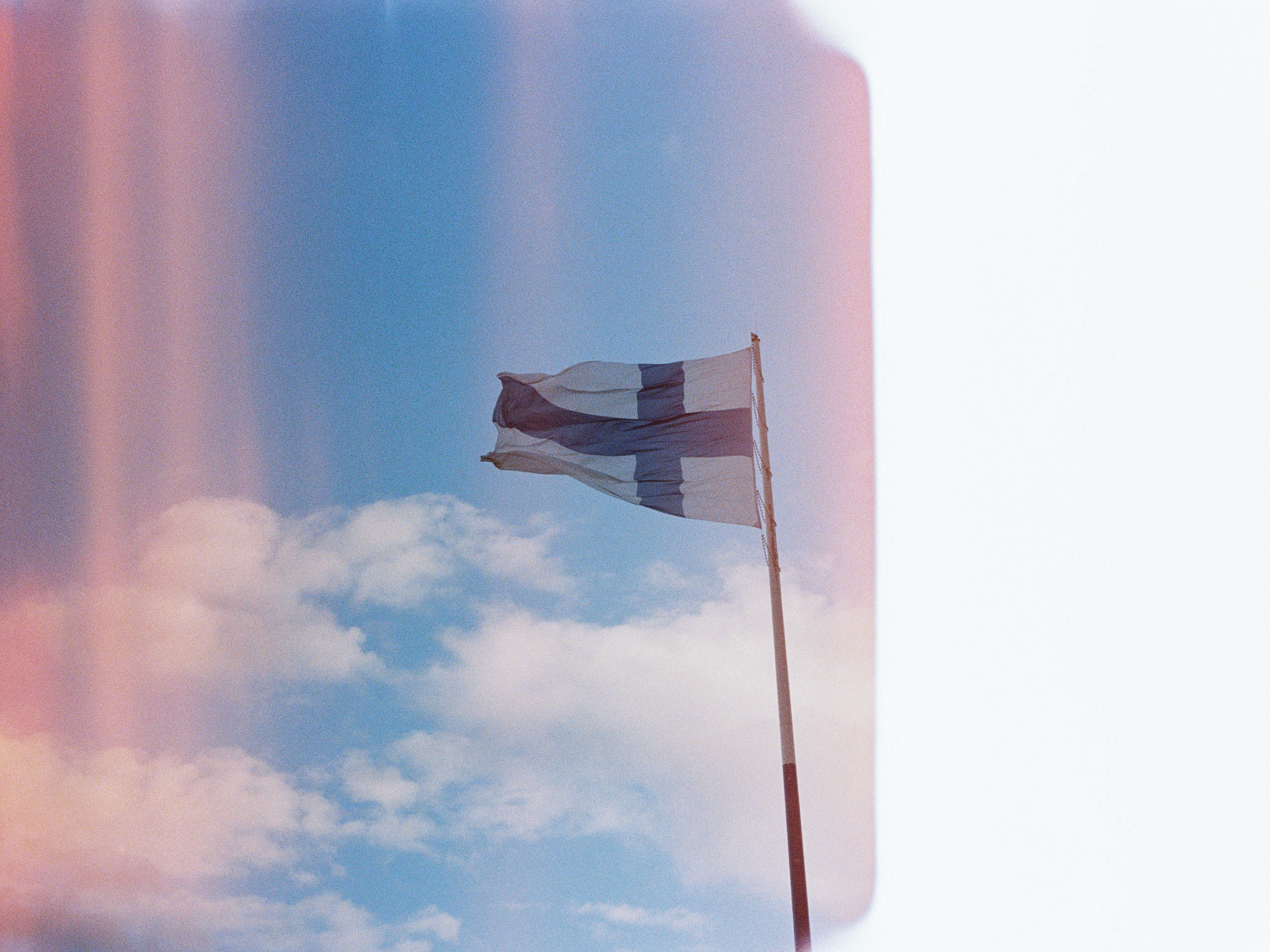 Finnish flag waving against a cloudy blue sky