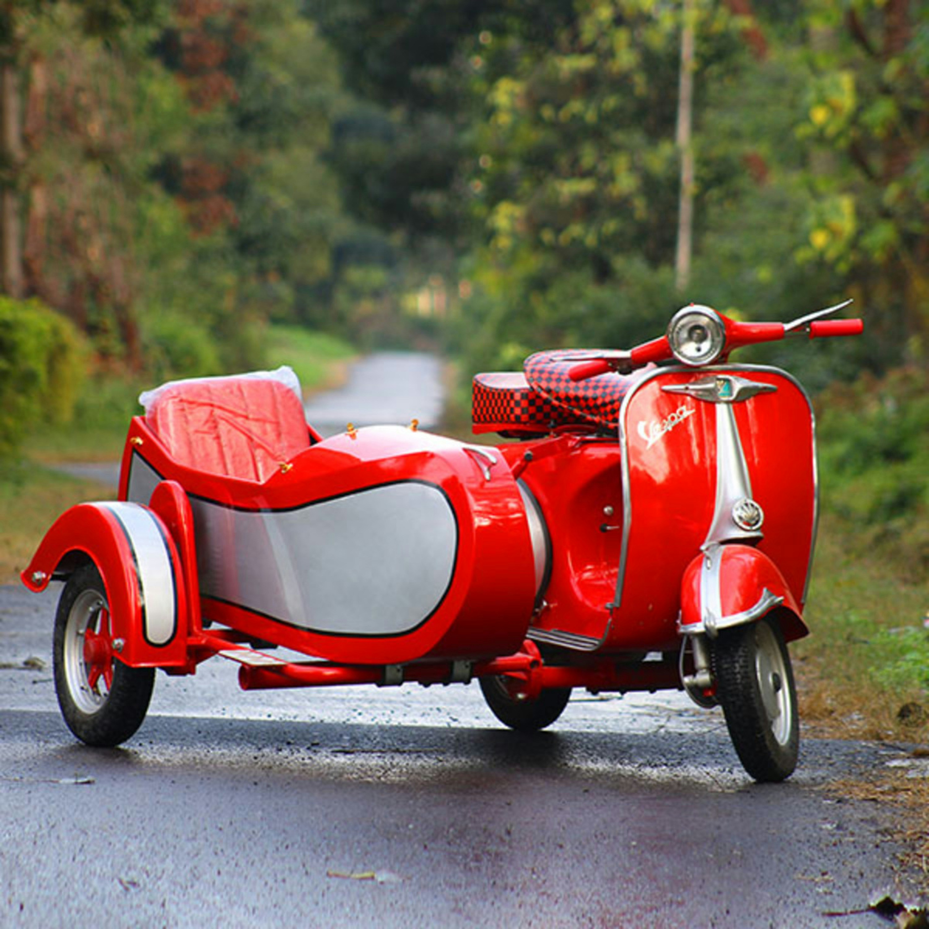 Uma scooter vermelha vintage com um sidecar na rua