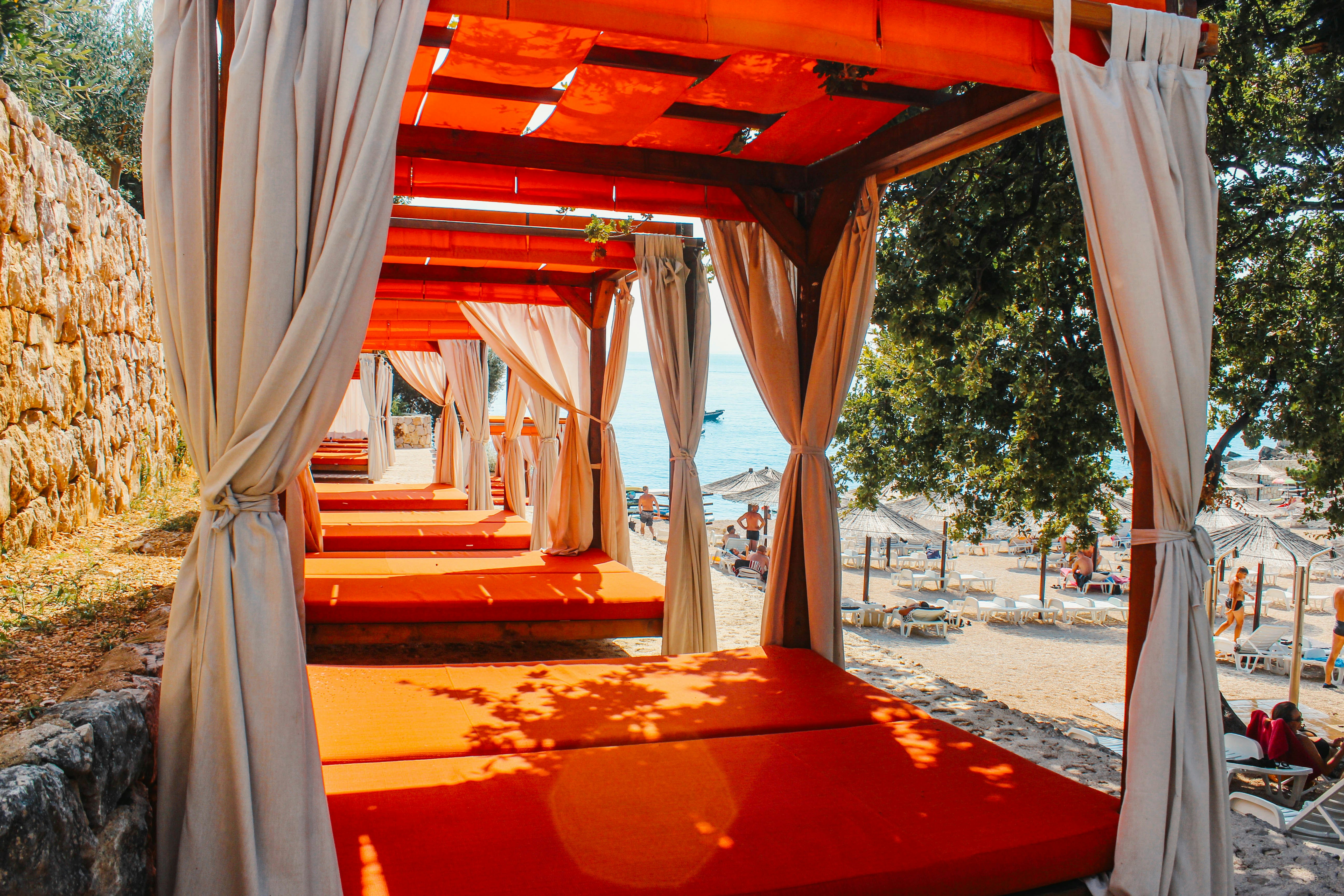 Orange lounge beds with curtains on a sunny beach