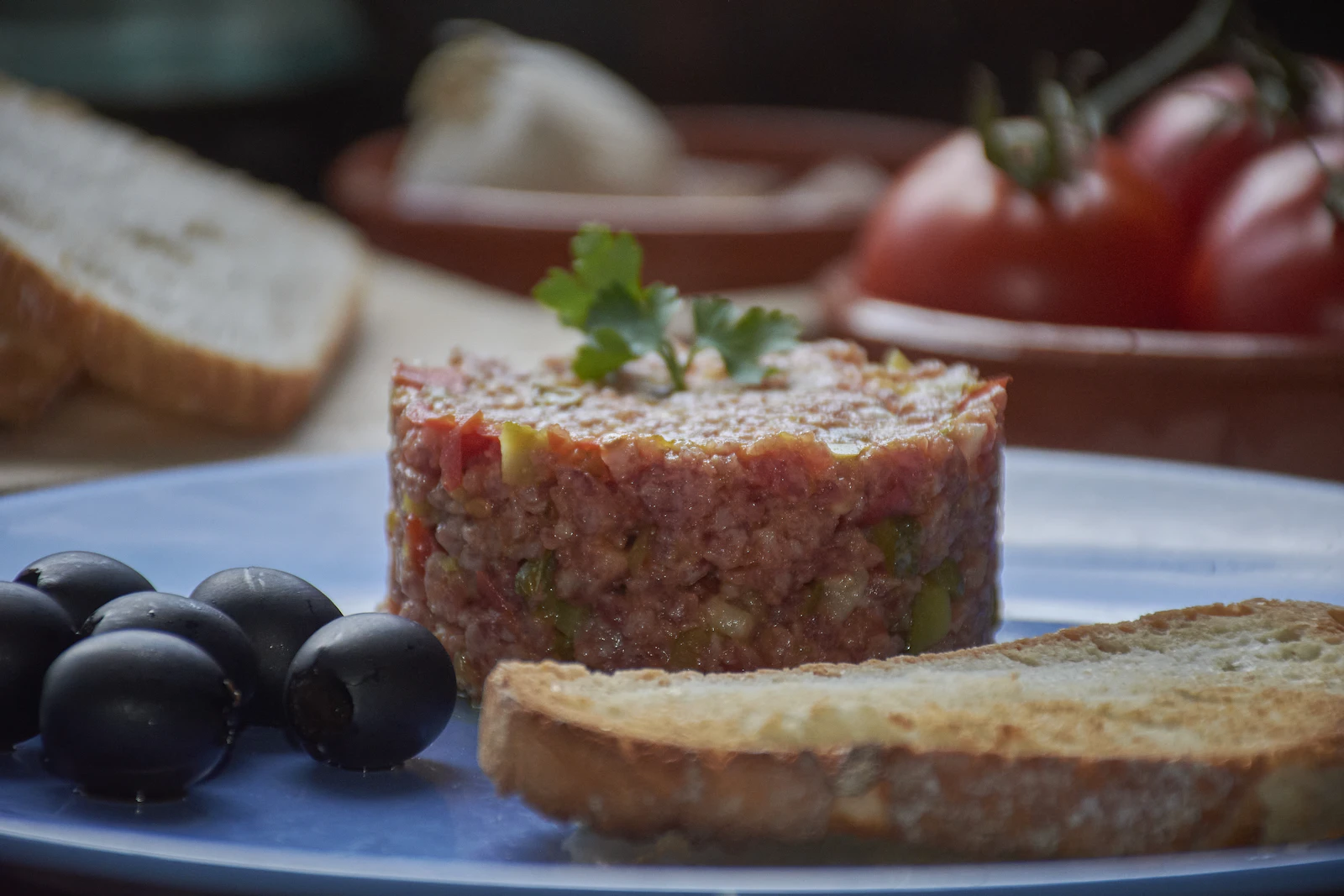 Đĩa beef tartare cao cấp trang trí với ô liu, bánh mì và cà chua bi