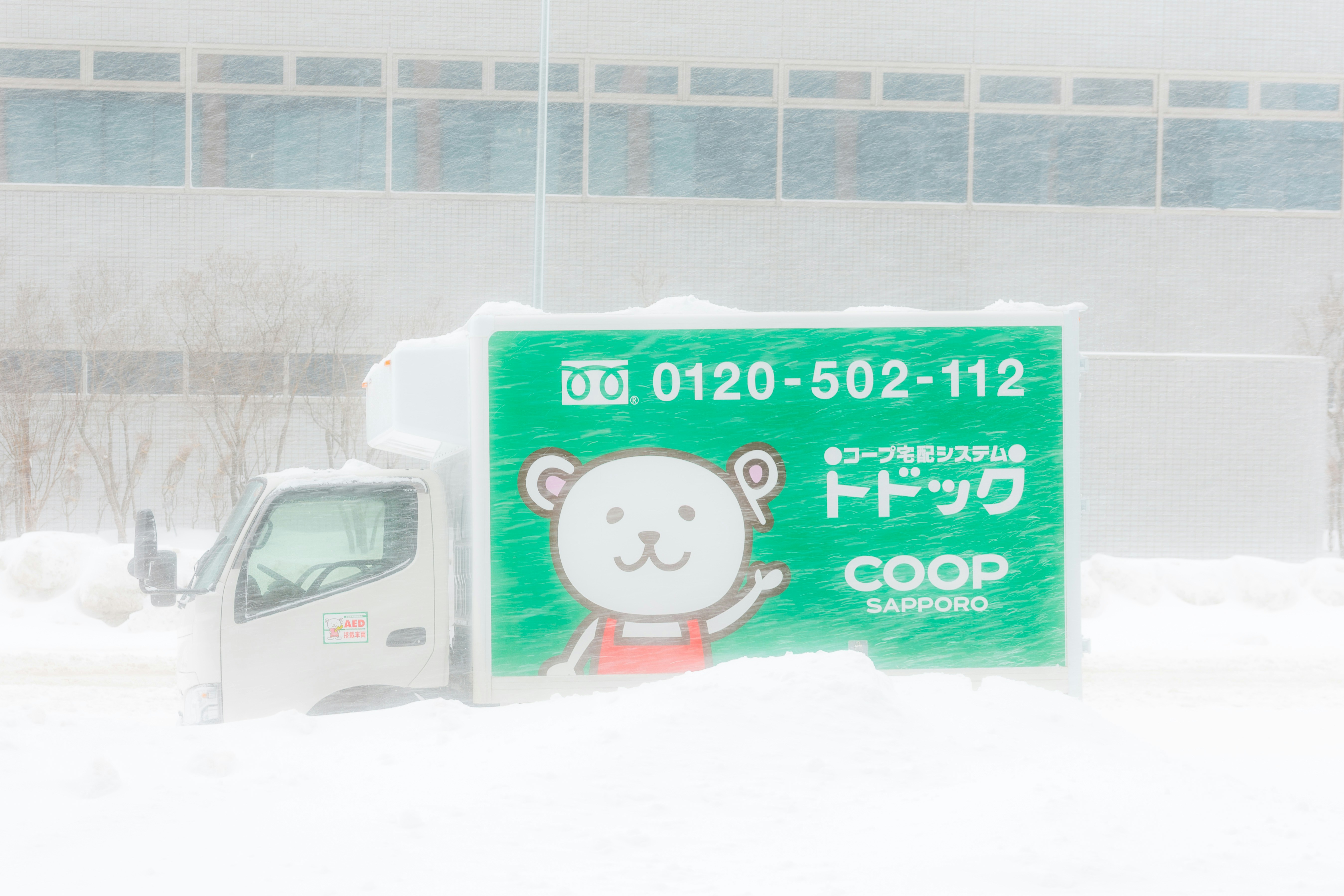 A truck covered in snow with a cartoon bear logo.