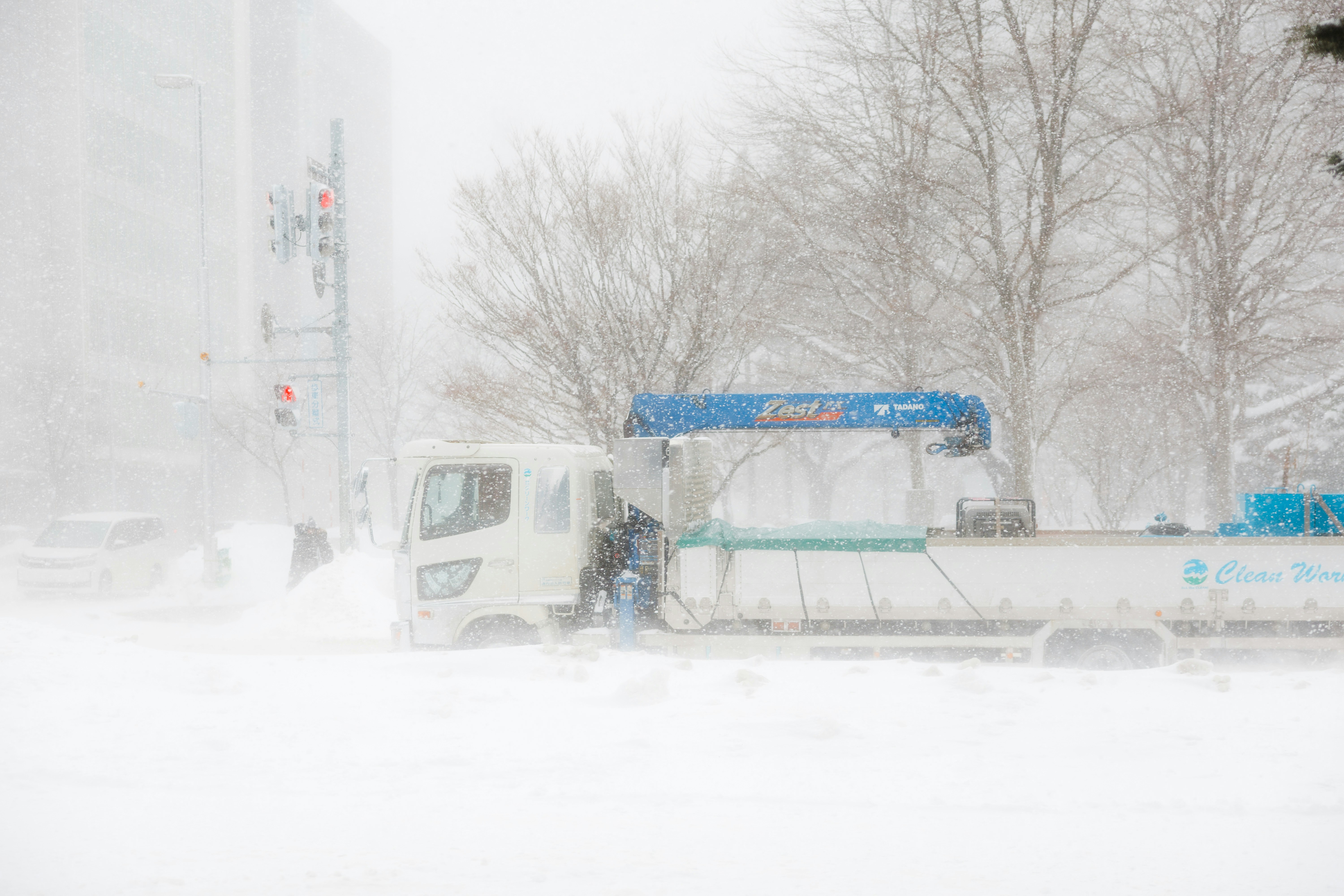 White truck with crane in heavy snowstorm