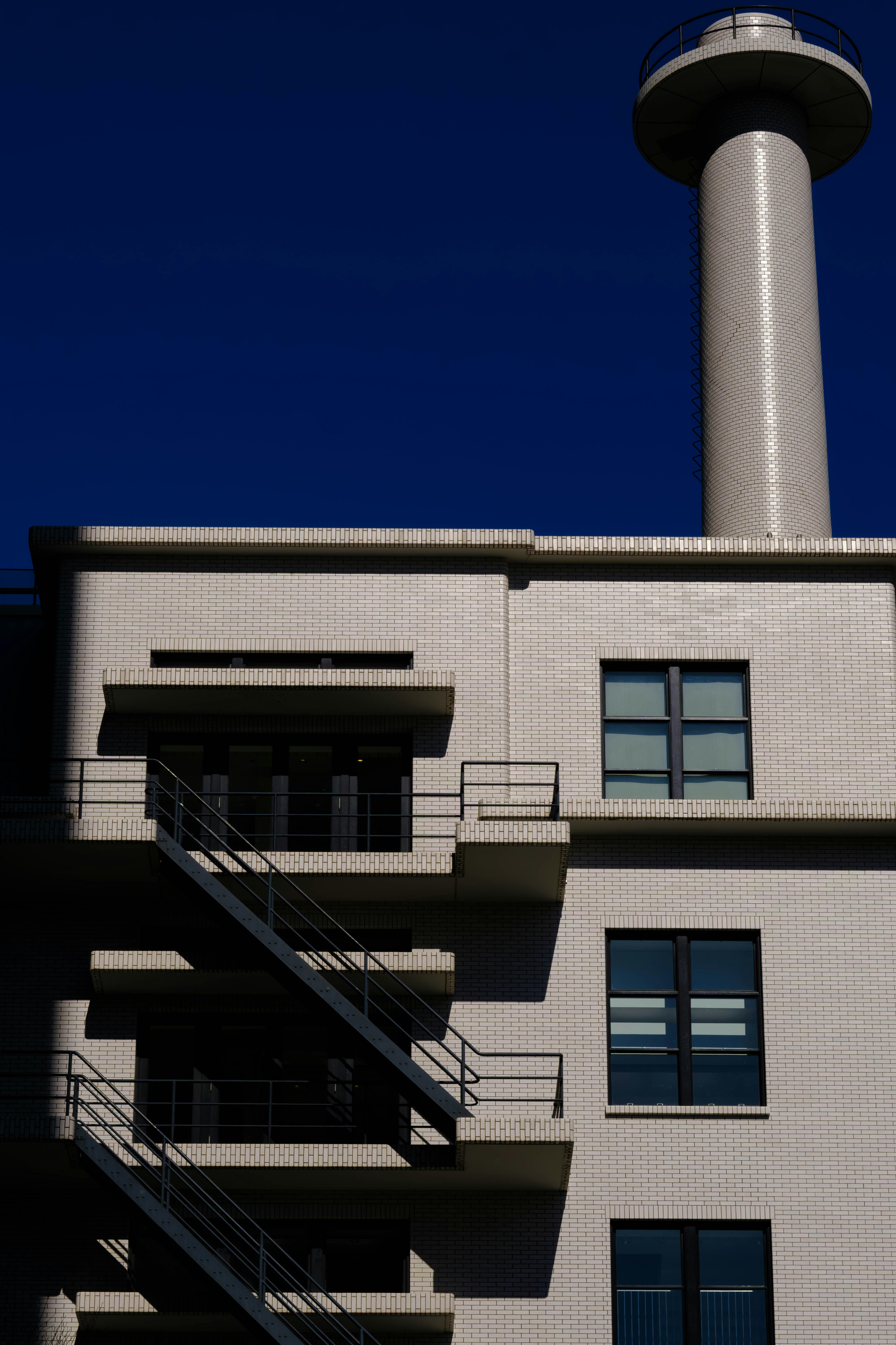 Modern building with a tall chimney against blue sky