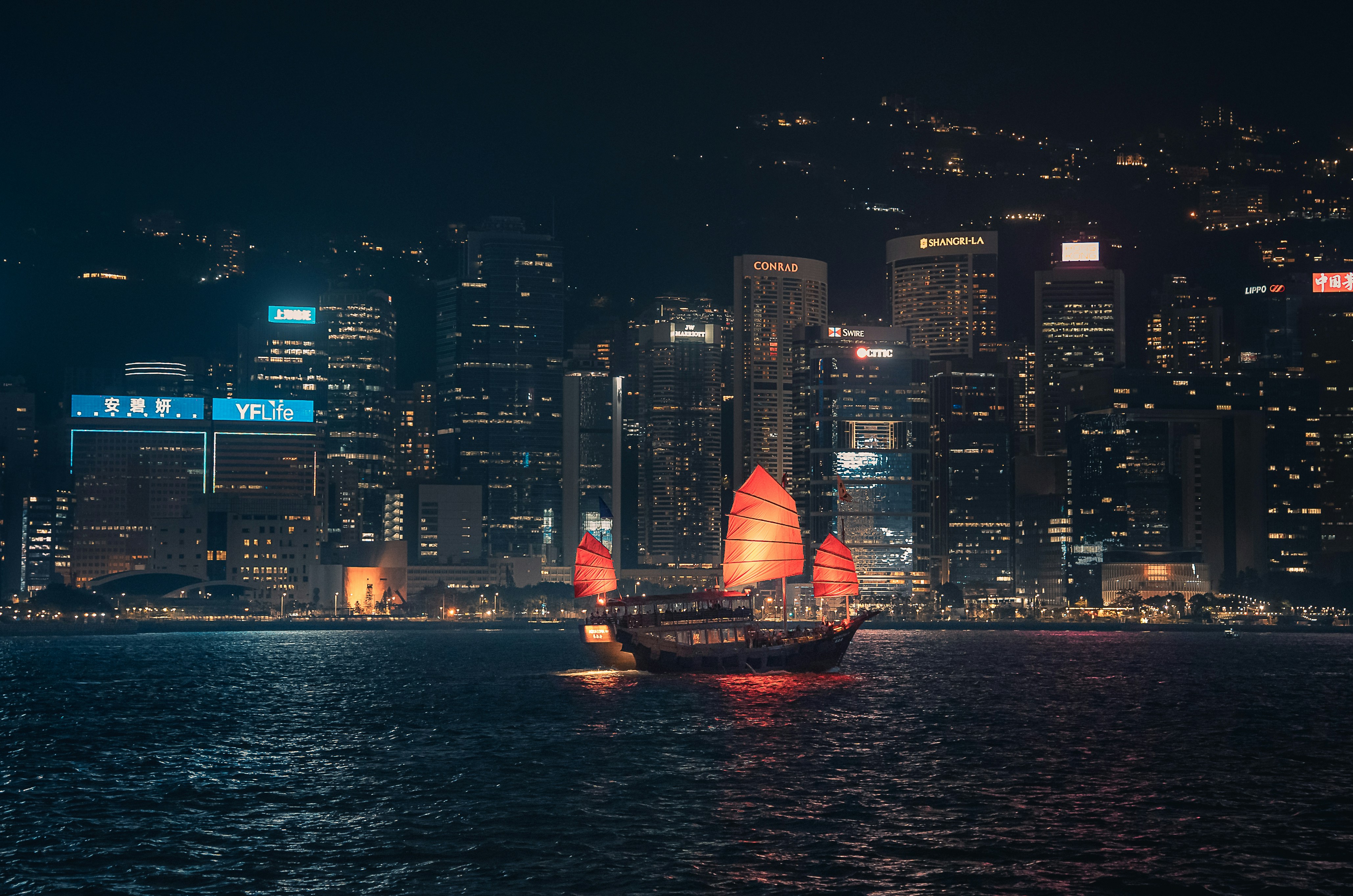 A traditional junk boat sails on the water at night.
