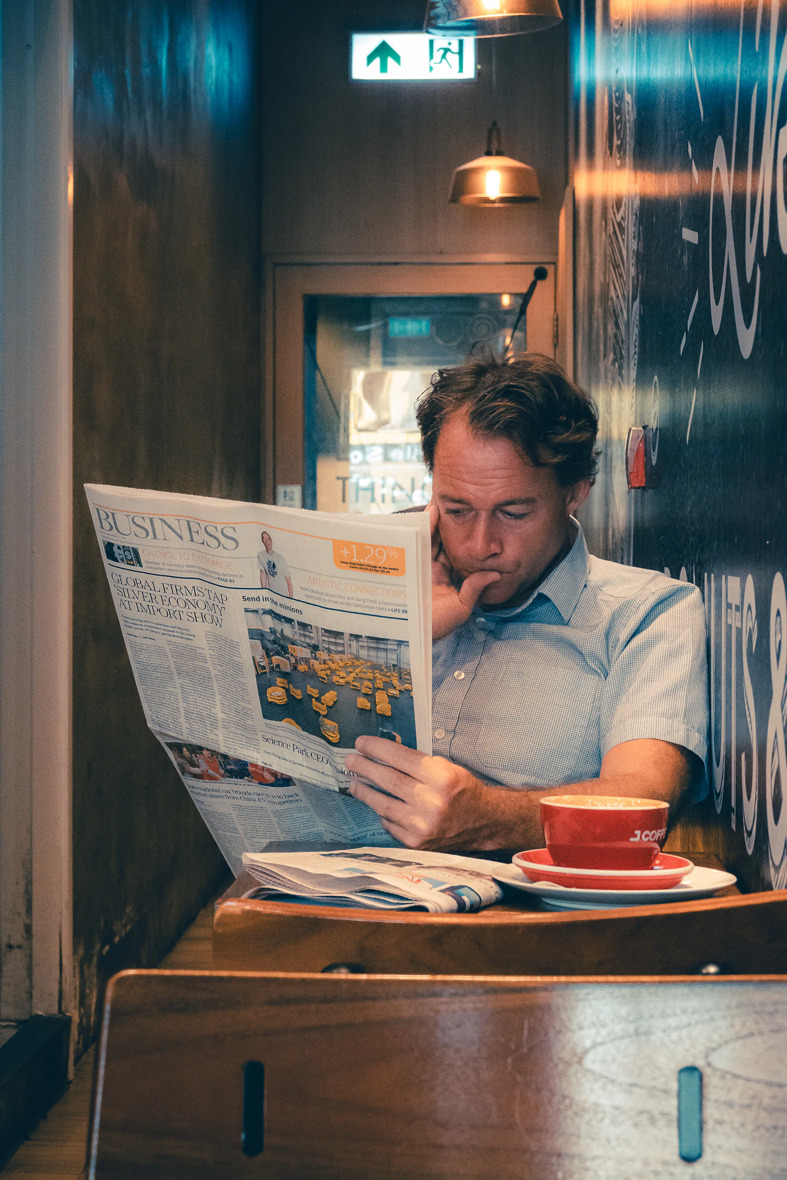 A man reading a newspaper with a coffee