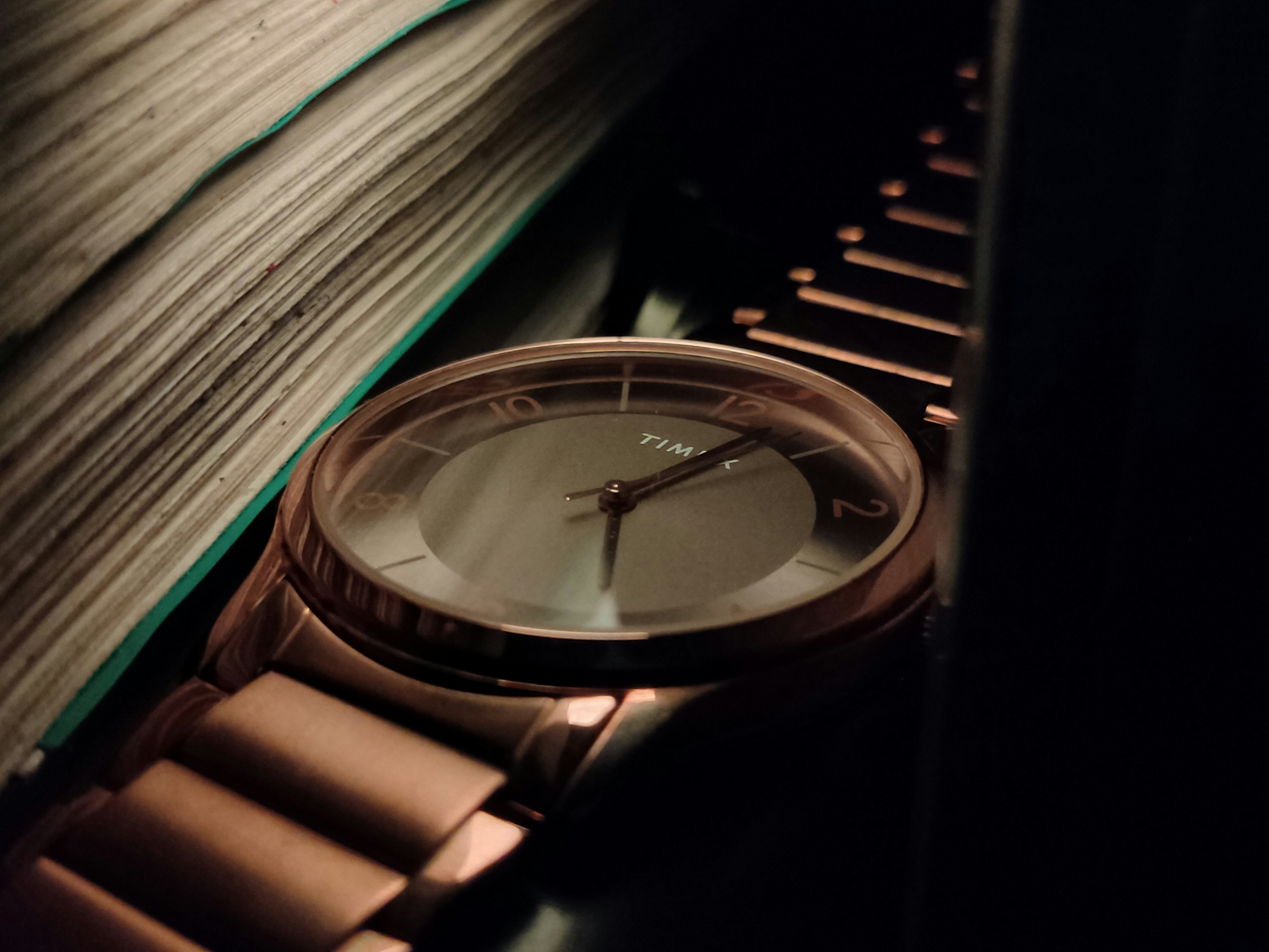 Close-up of a rose gold watch next to books